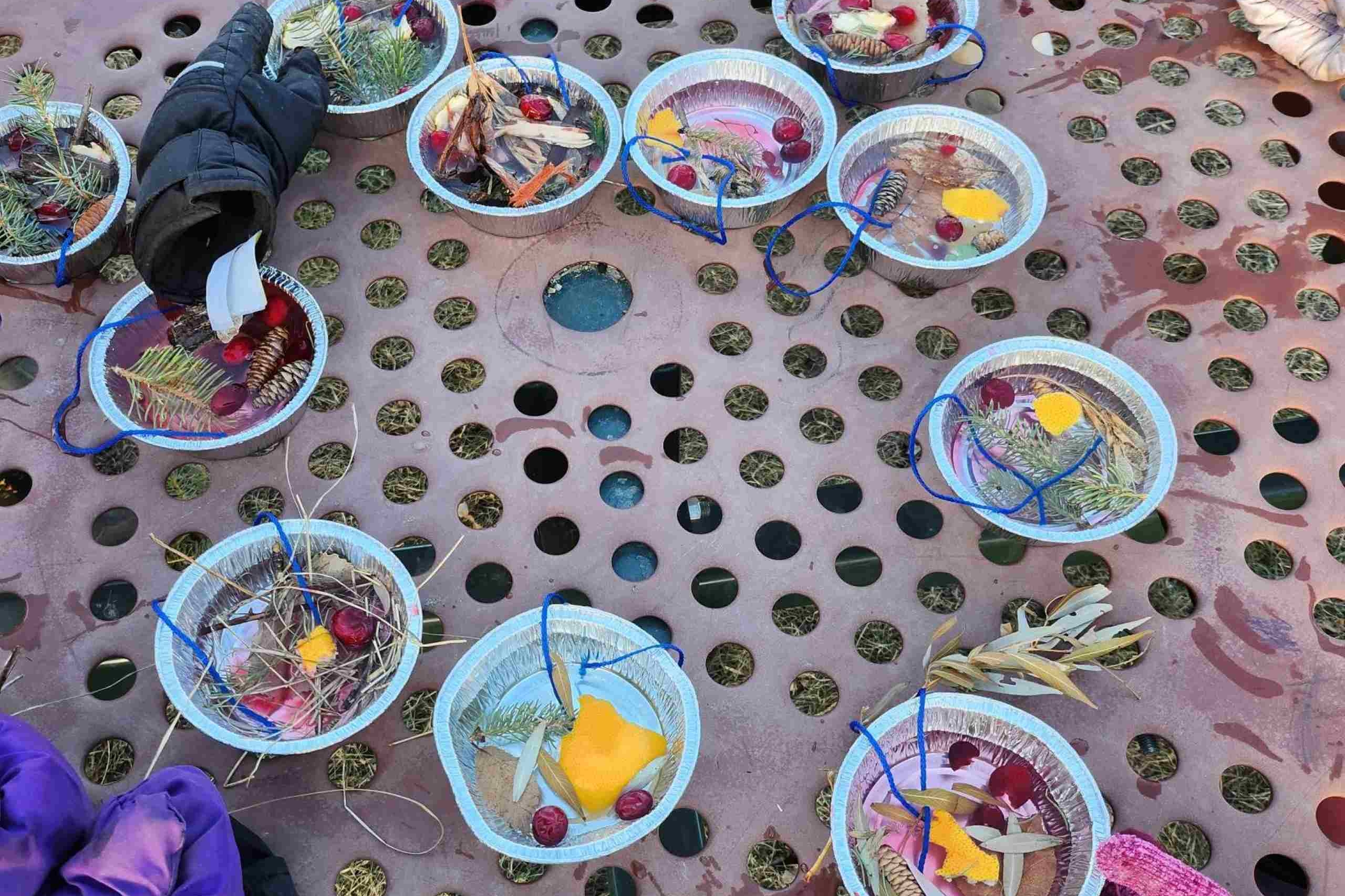 Bowls with water and leaves are on a picnic table outside.