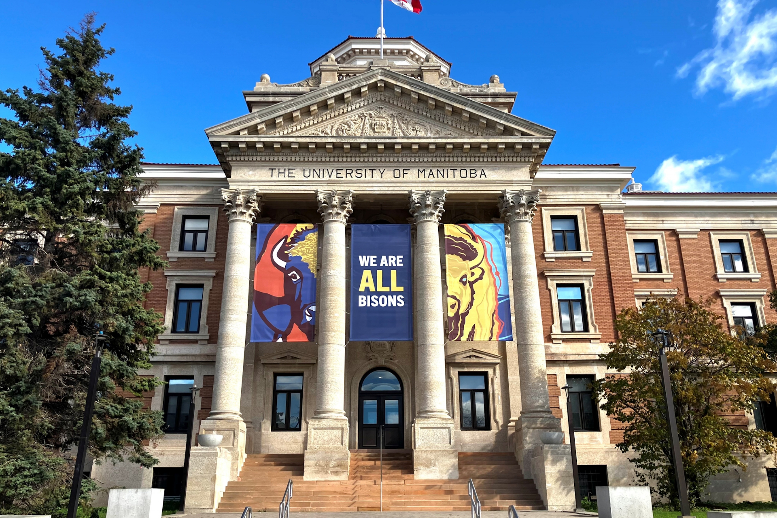 Banners of two half bison attached to an administration building with a centre banner with text reading: "We are all bisons"