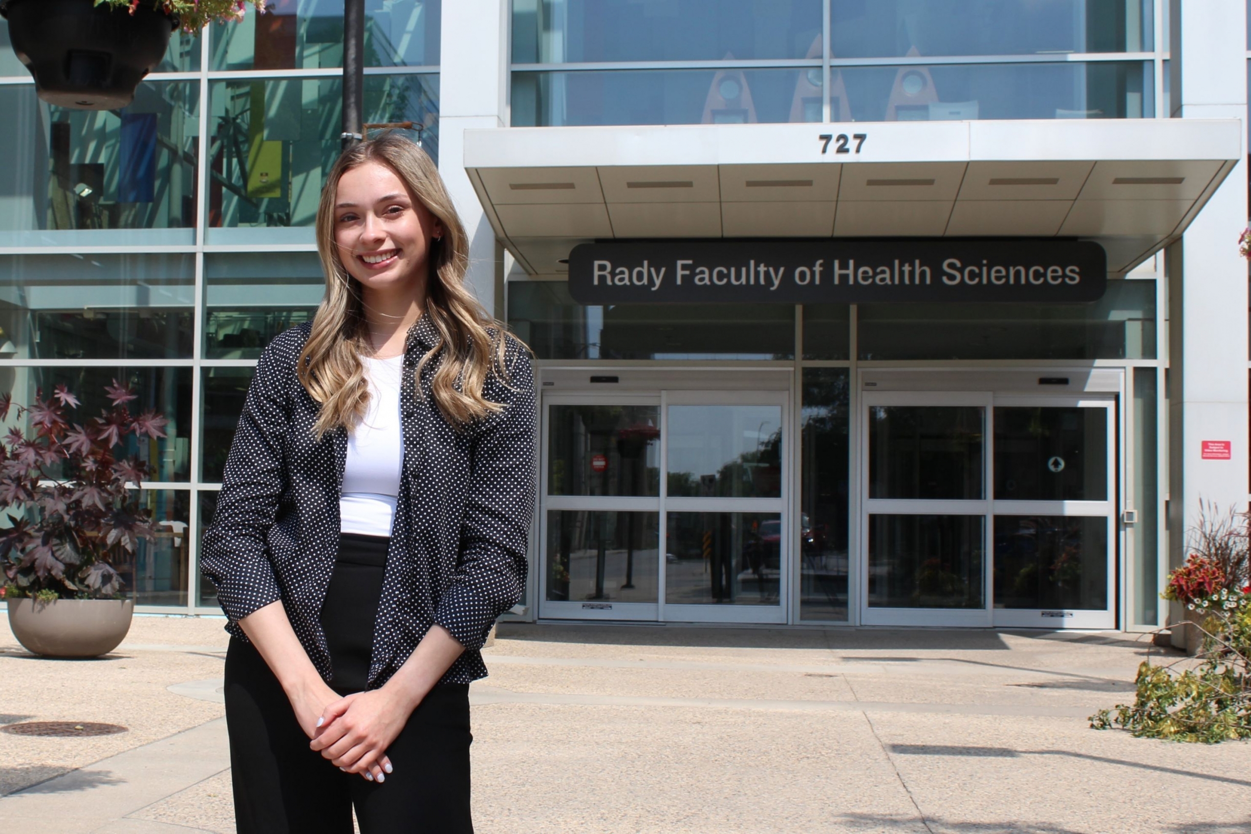Student Alexa Pommer standing outside the Rady Faculty of Health Sciences Brodie Atrium.