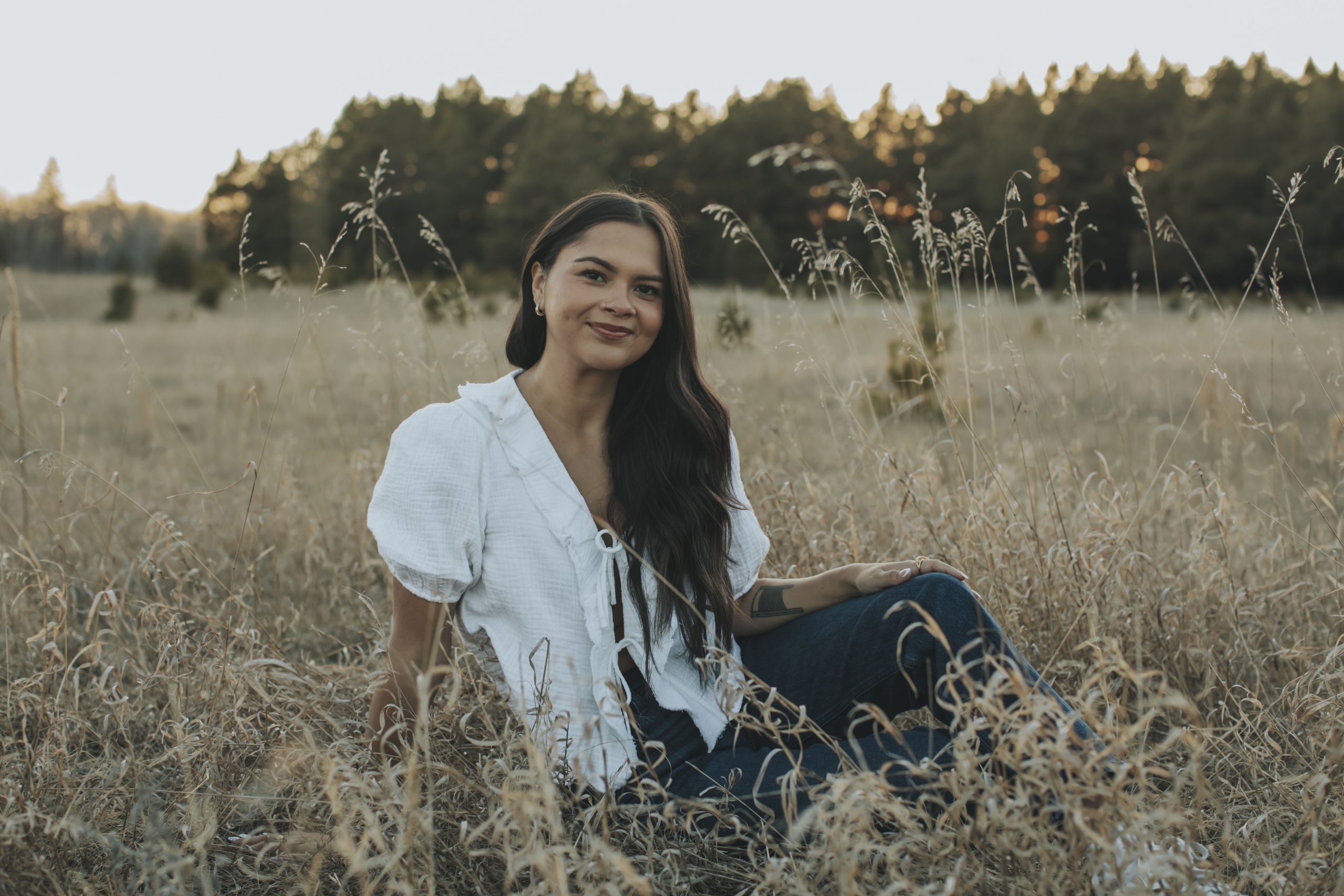 Woman sits in tall prairie grass.
