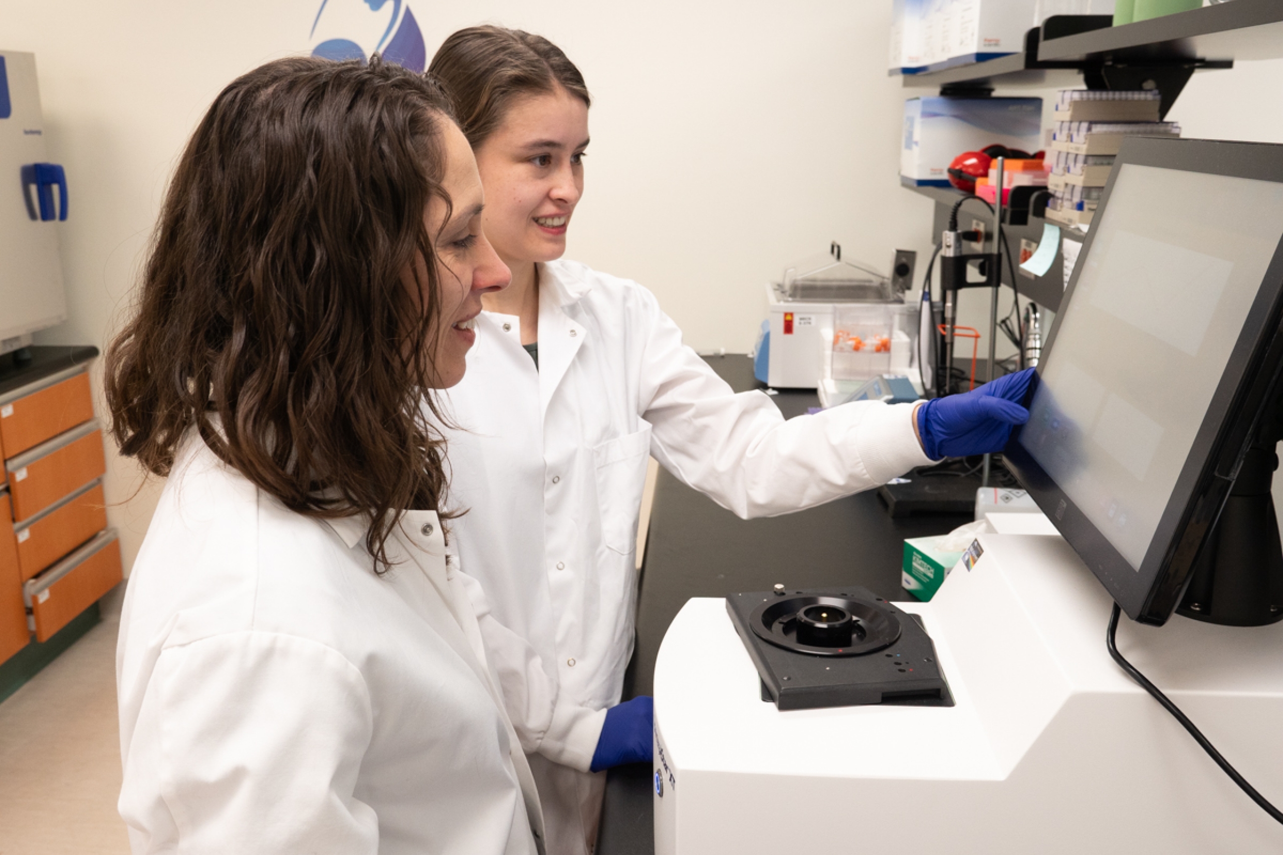 Two people working in a lab, looking at an equipment's screen.