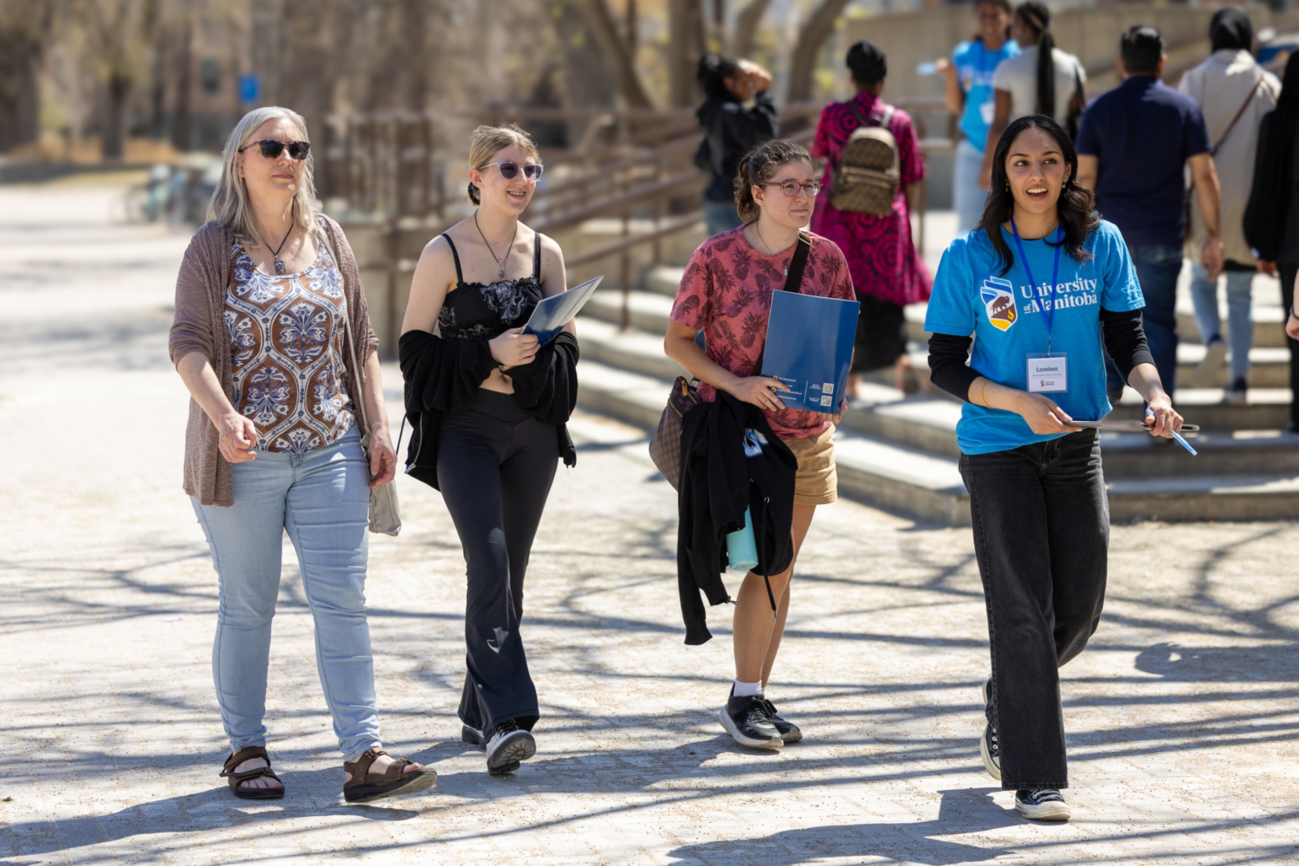 Preparing for University volunteer tour guide leading three people around campus in front of UMSU University Centre