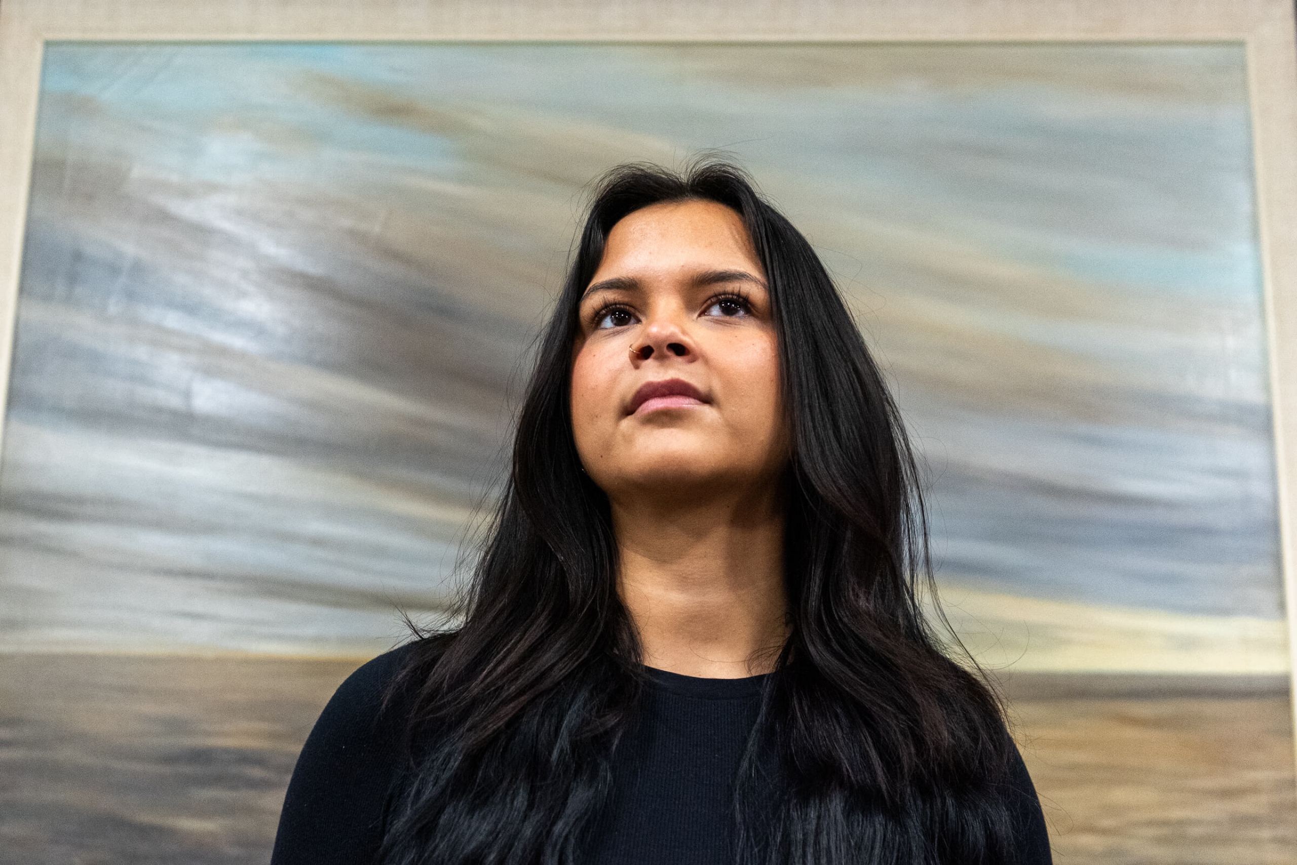Antonina Kandiurin stands in front of a painting of the tundra