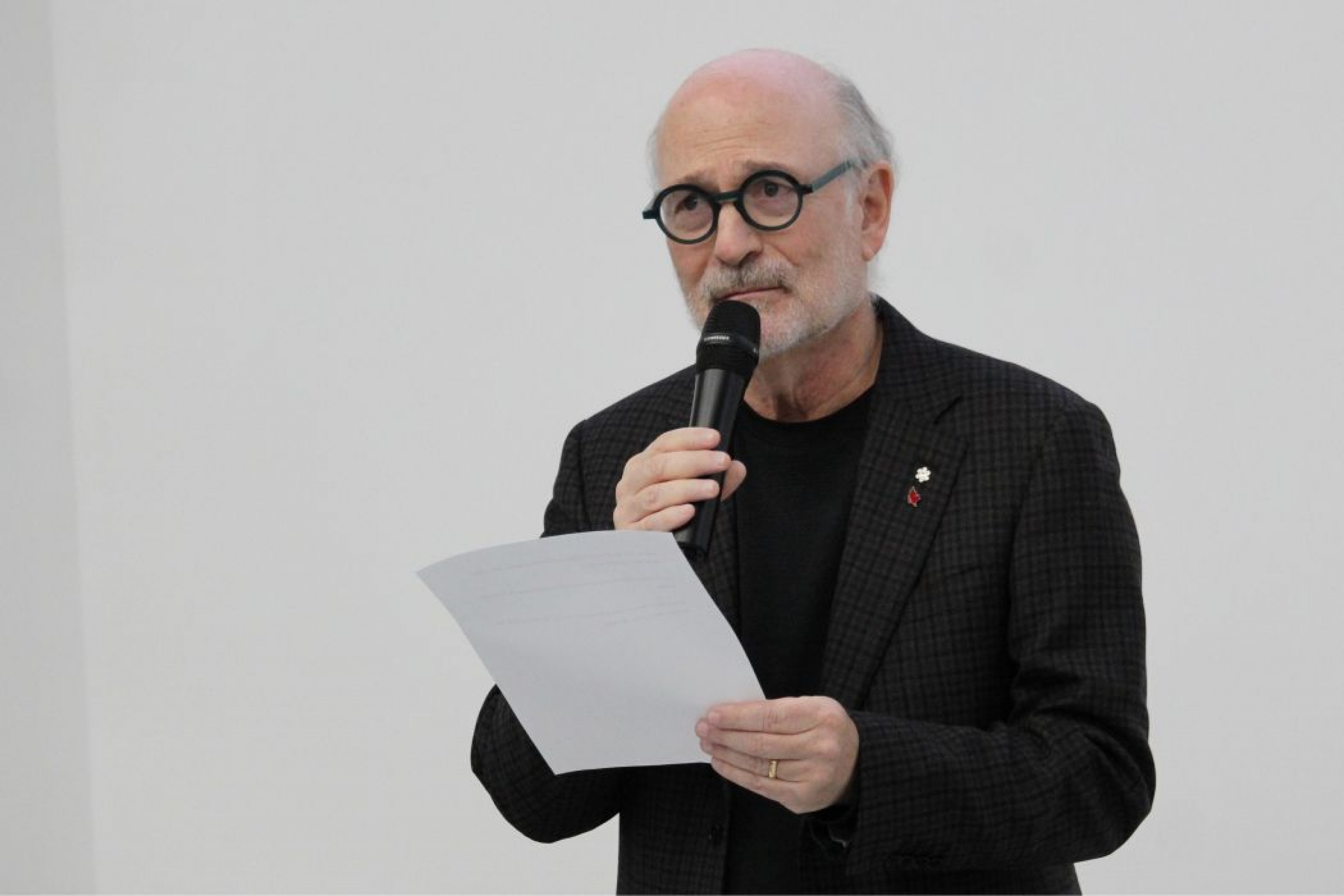 Dr. Harvey Chochinov speaks into a microphone while holding a piece of paper.