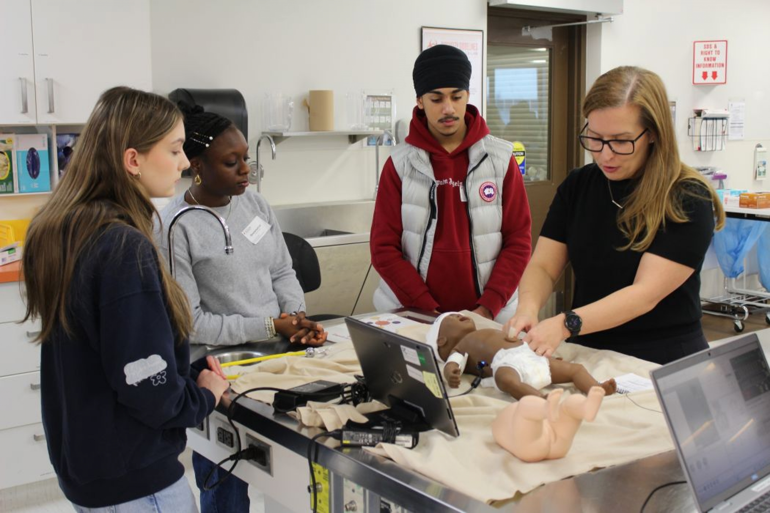 An instructor demonstrates medical skills using a baby training manikin.