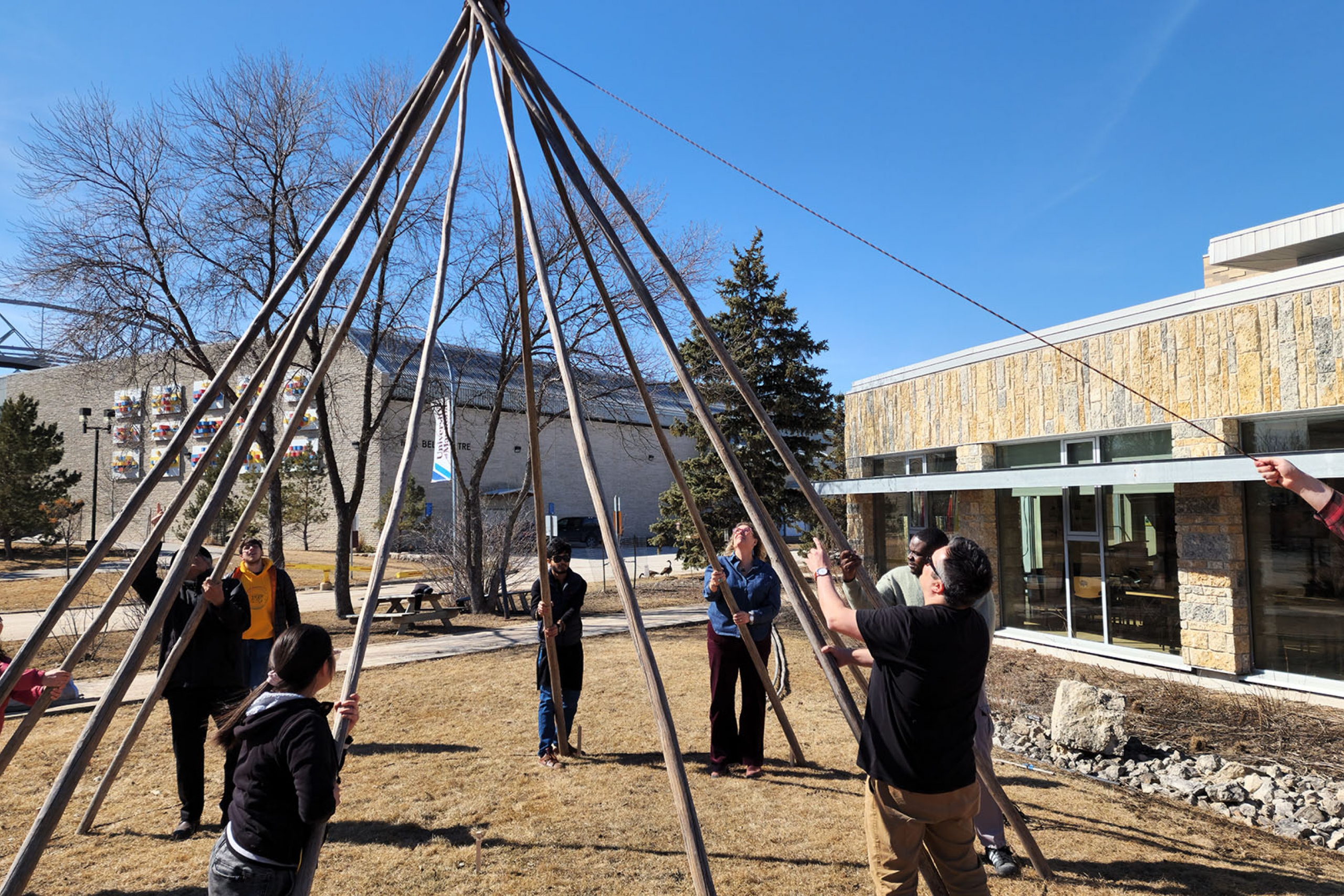 A group of people building a tipi outside