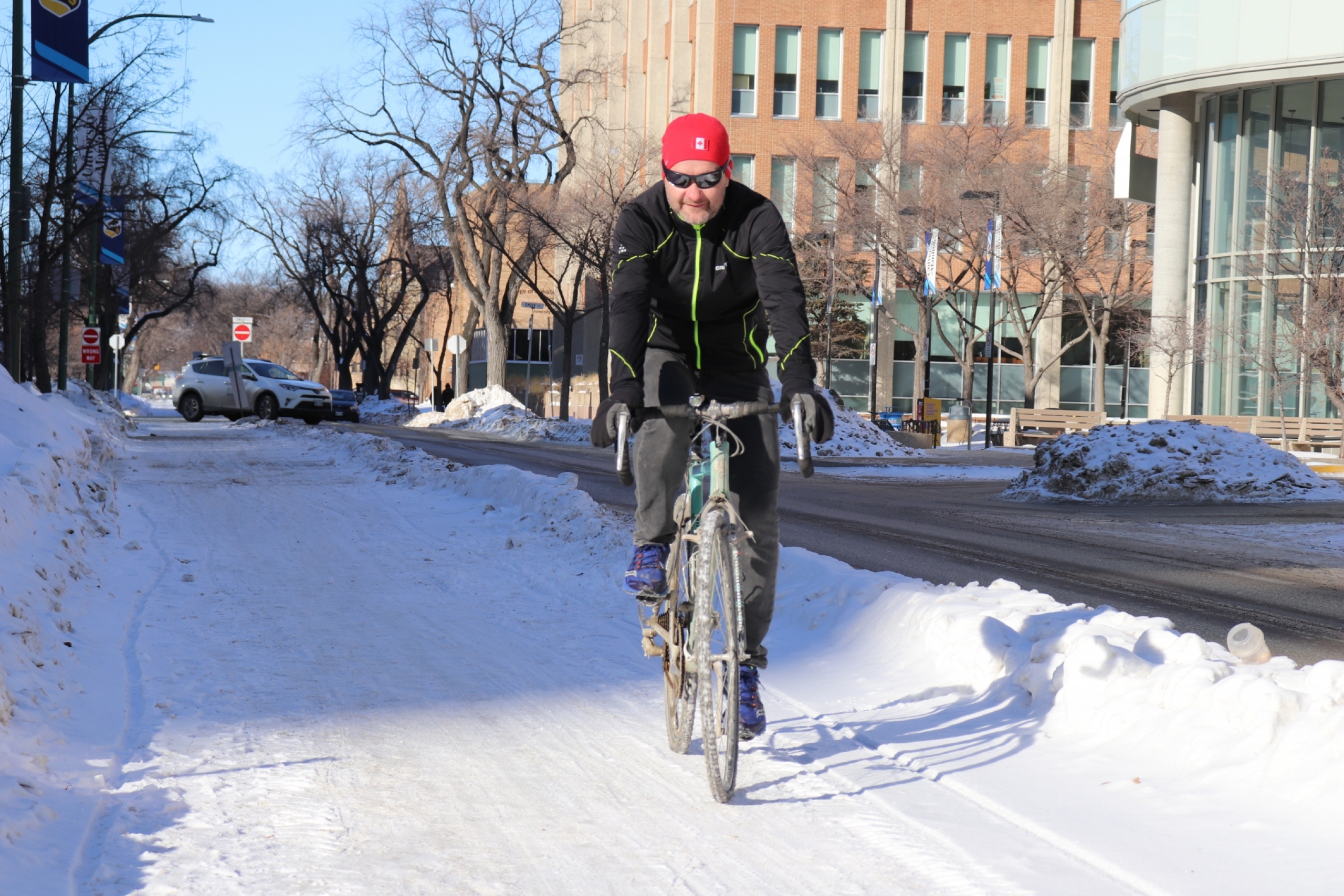 Dr. Jon McGavock rides a bicycle in a bike lane in the winter. 