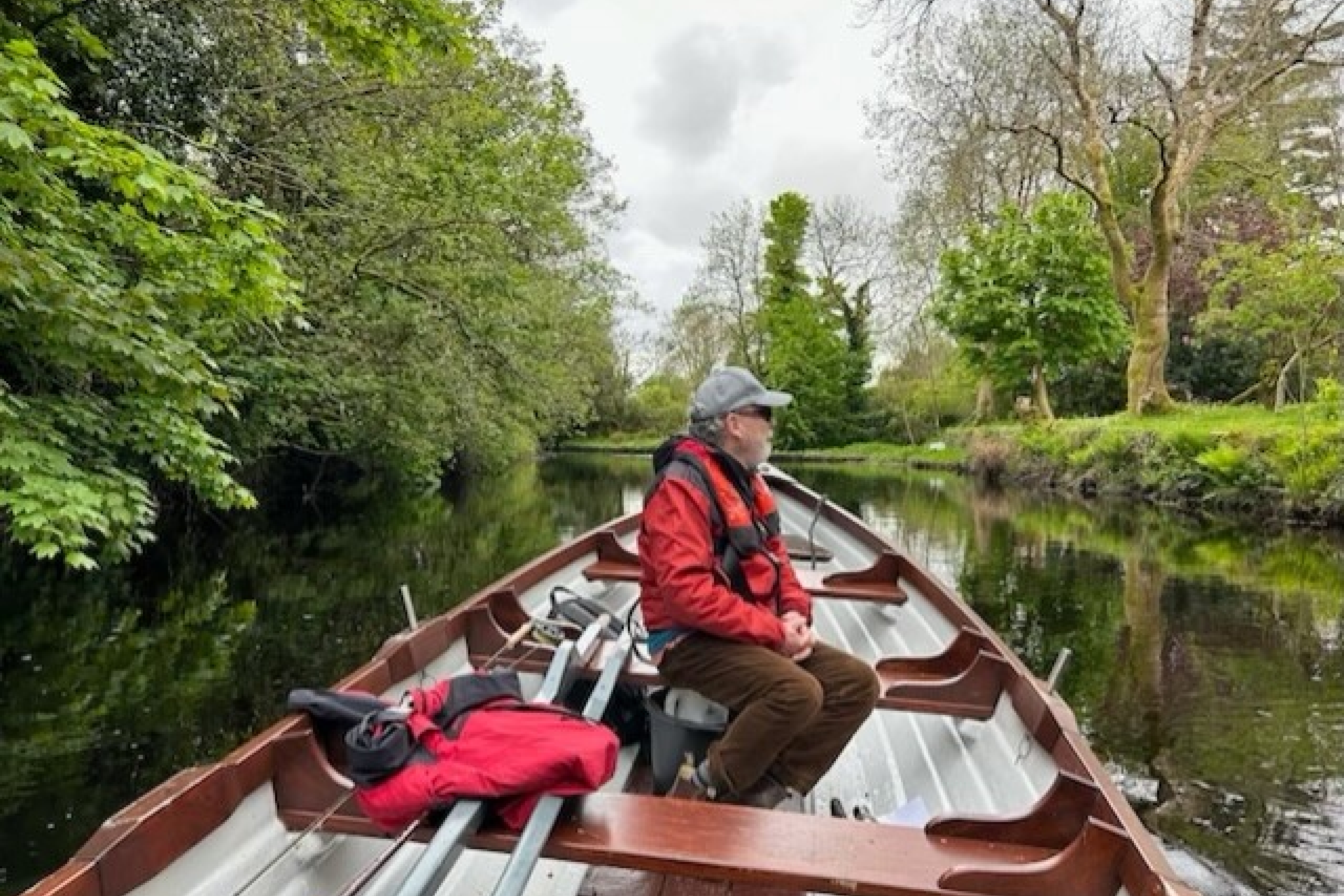 Dr. John Sinclair appears on a boat on top of a river, looking out to the nature surrounding him.