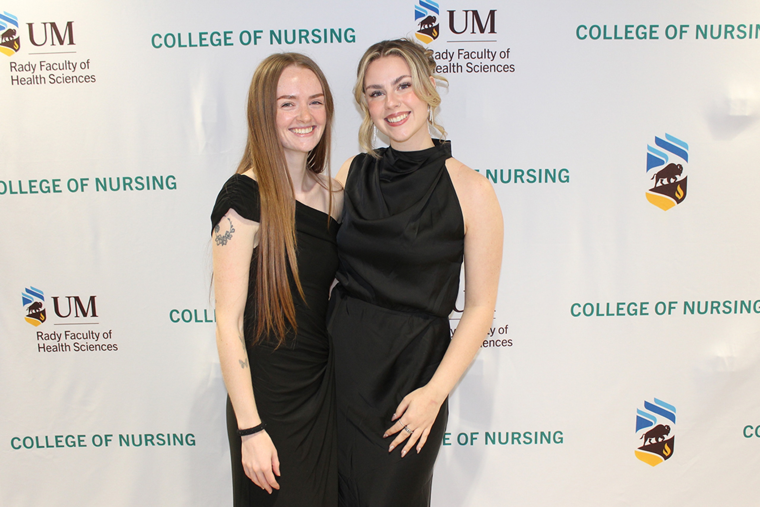 Olivia Steininger and Sarah Livingstone in front of a University of Manitoba College of Nursing banner.