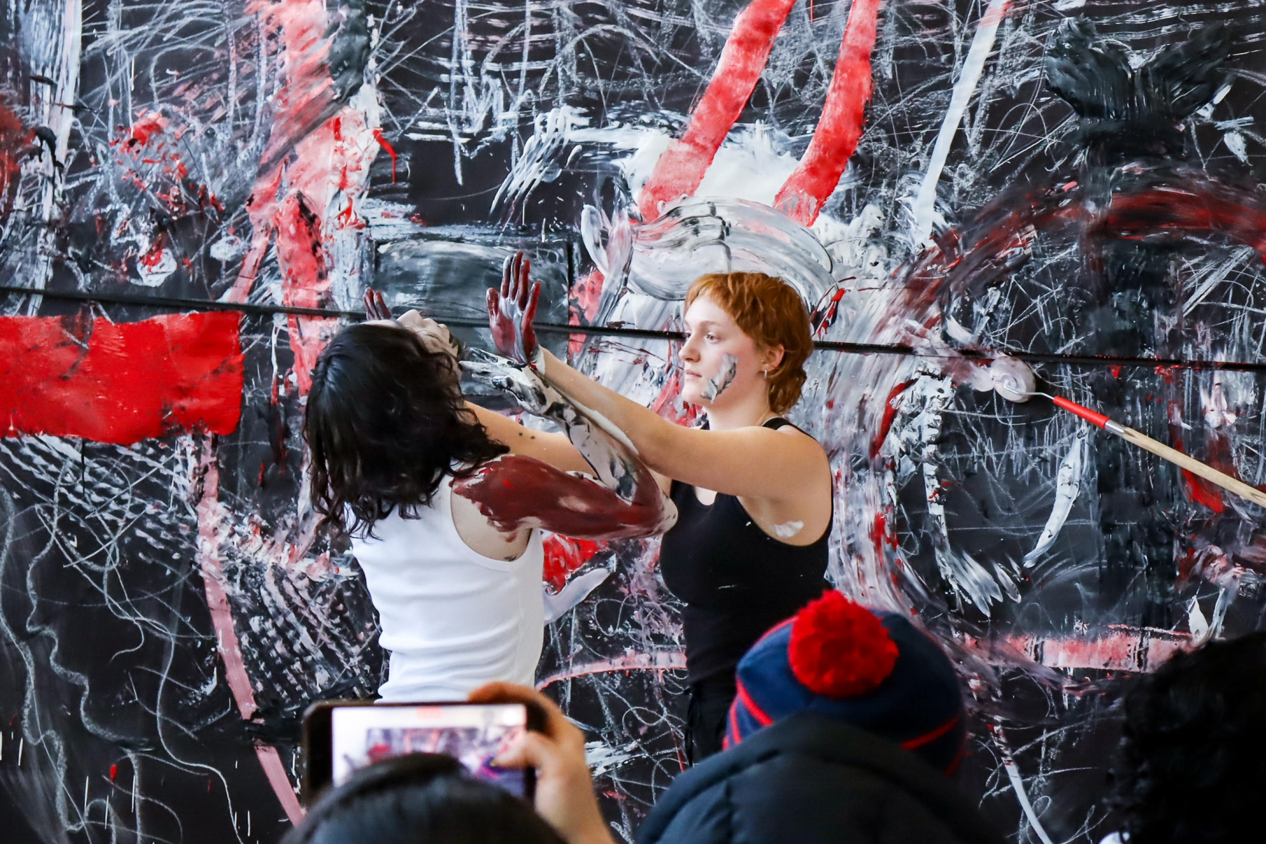 Two School of Art students paint a large abstract canvas during a live interdisciplinary performance.