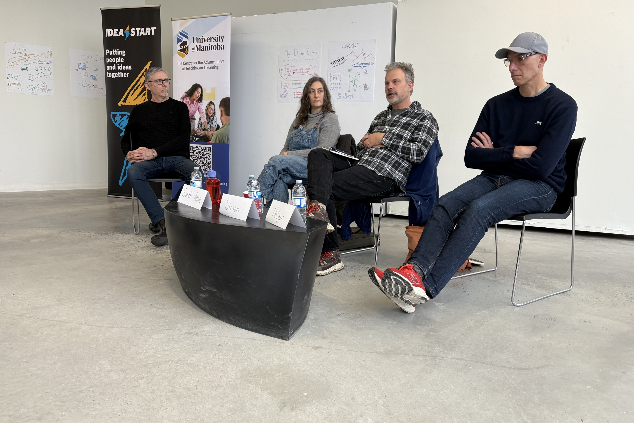Four people sitting on chairs answering questions in a panel-like discussion.