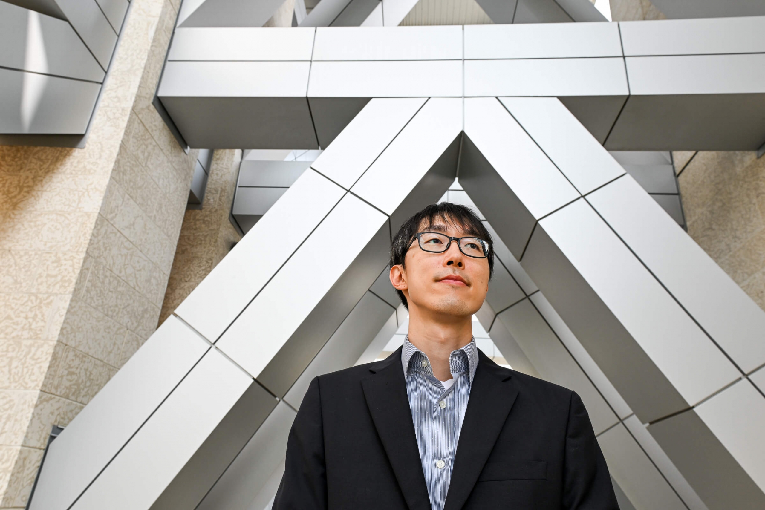 Jae Yun Kim stands below architectural supports of a building