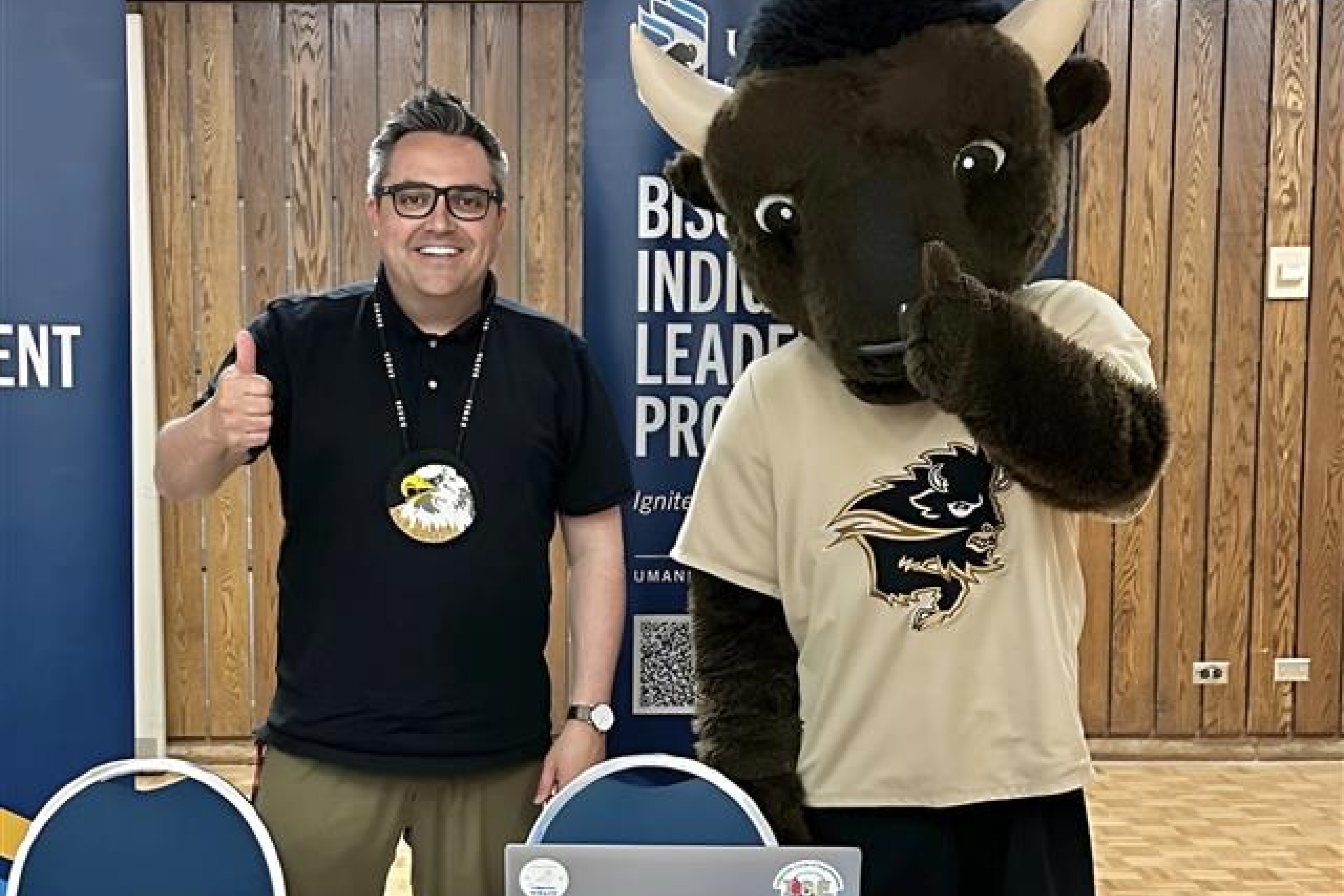 Justin Rasmussen gives a thumbs up while standing beside Billy the Bison mascot.
