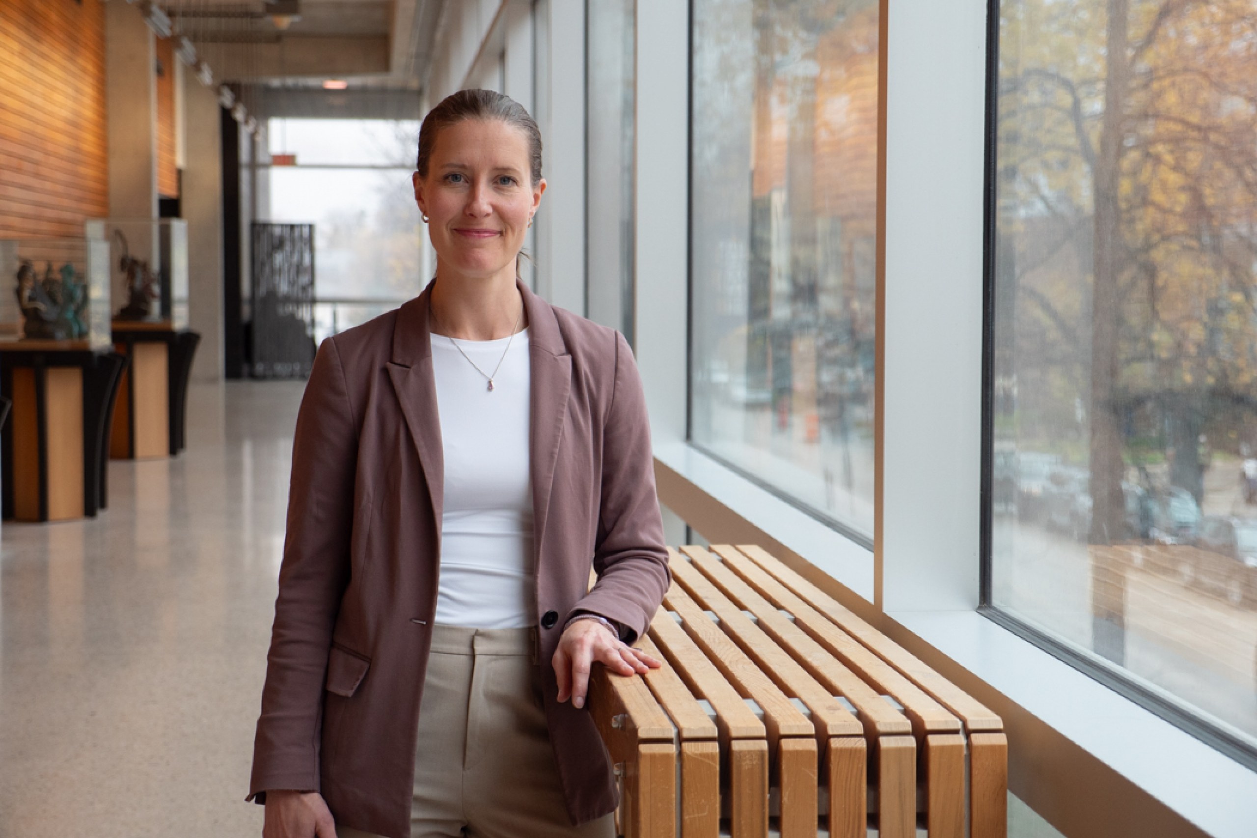 Dr. Kaarina Kowalec at a hallway, while standing and smiling at the camera.