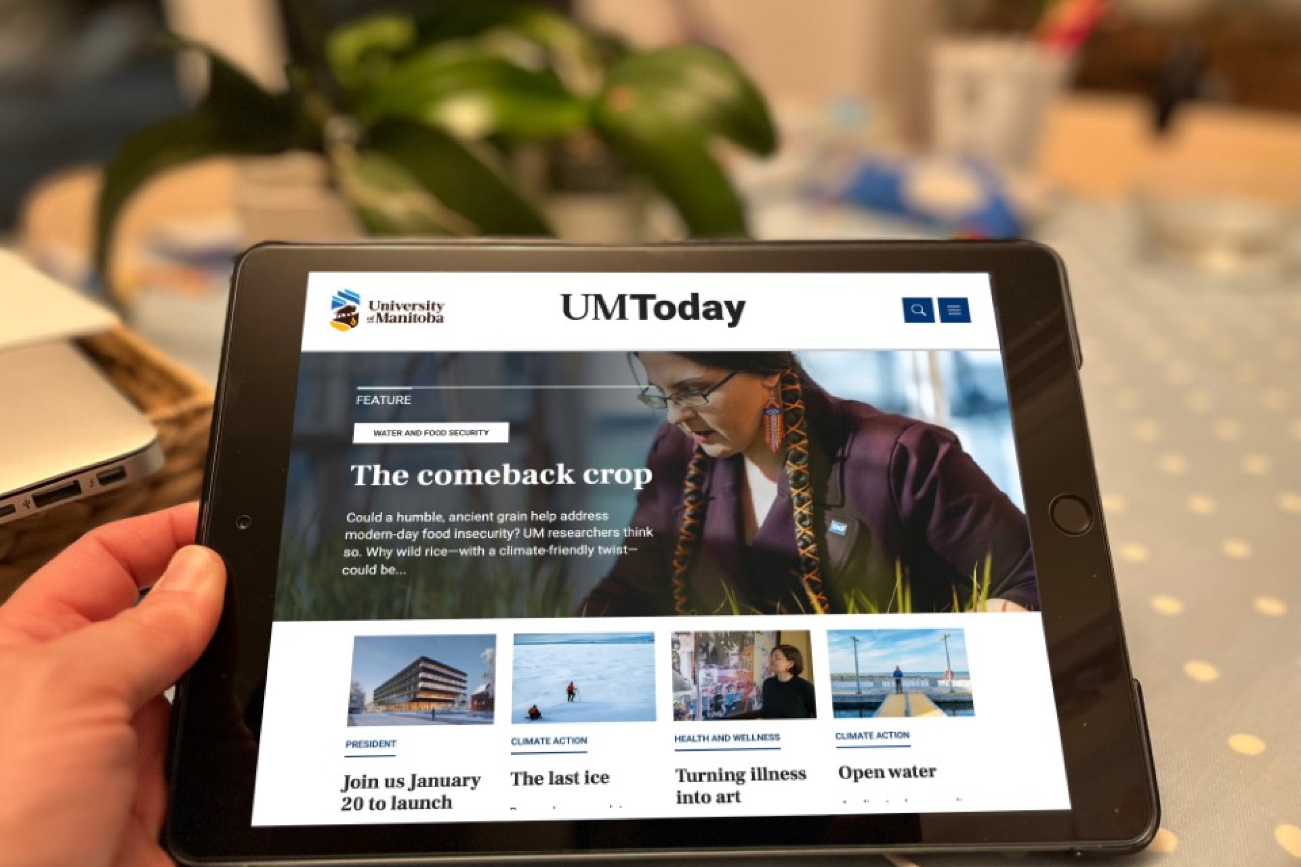 A person holding an ipad with the UM Today site displayed on the device.