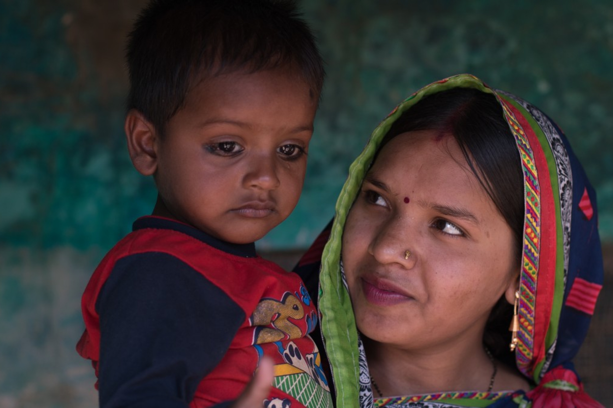 A toddler is pictured while the mother holds and looks at the child.