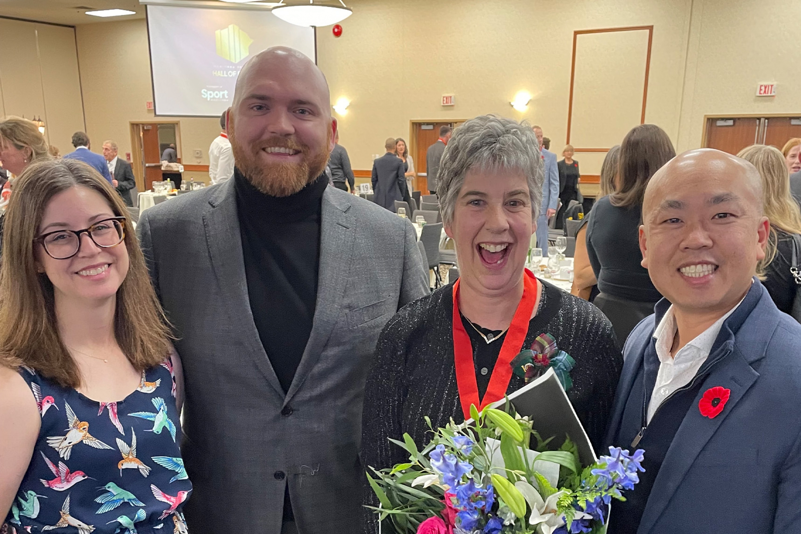 Brita Hall (centre right) holds a bouquet of roses and poses with Facilities team members.
