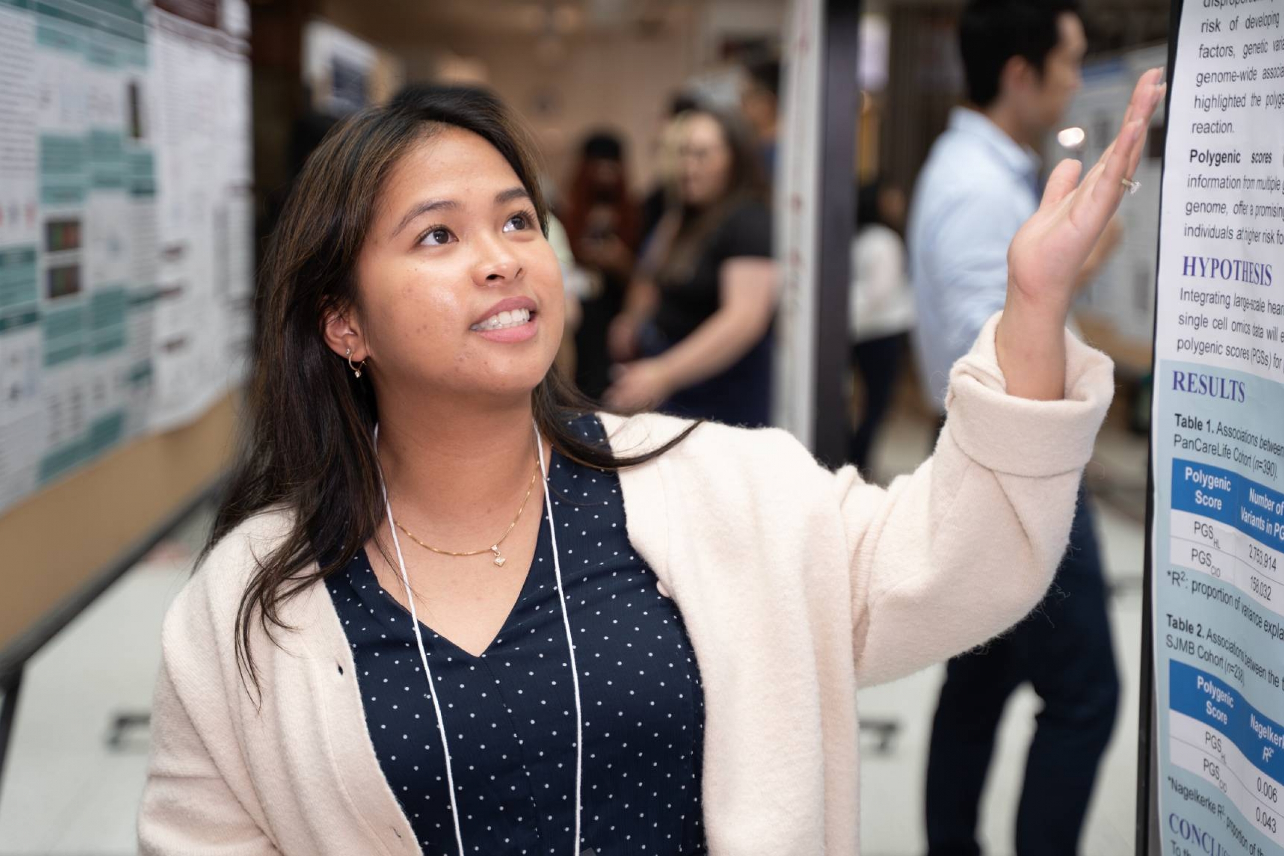 Student presenting research poster, gesturing towards the top part of the poster.
