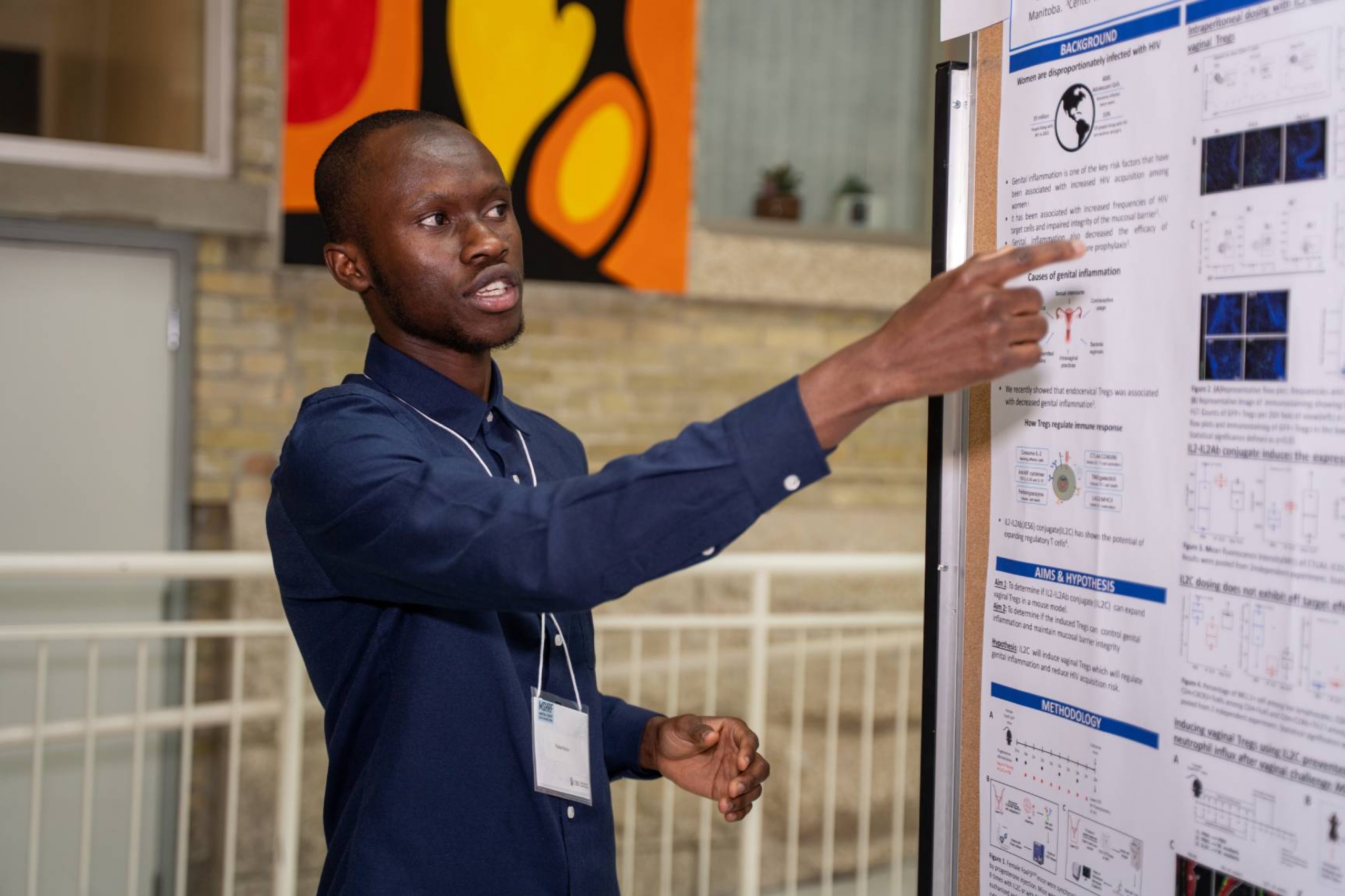 Student presenting research, pointing at the poster.