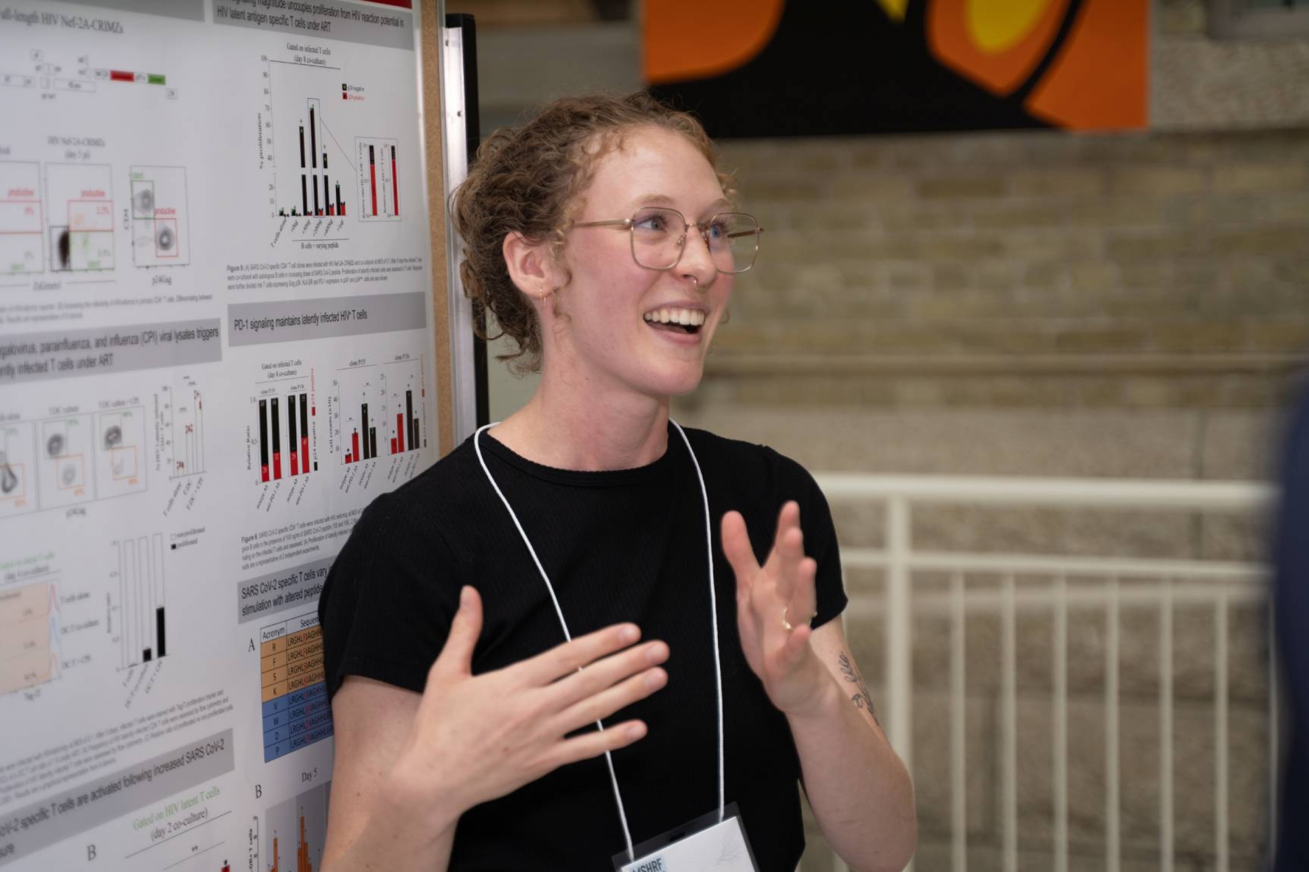 Student smiles while presenting research poster.