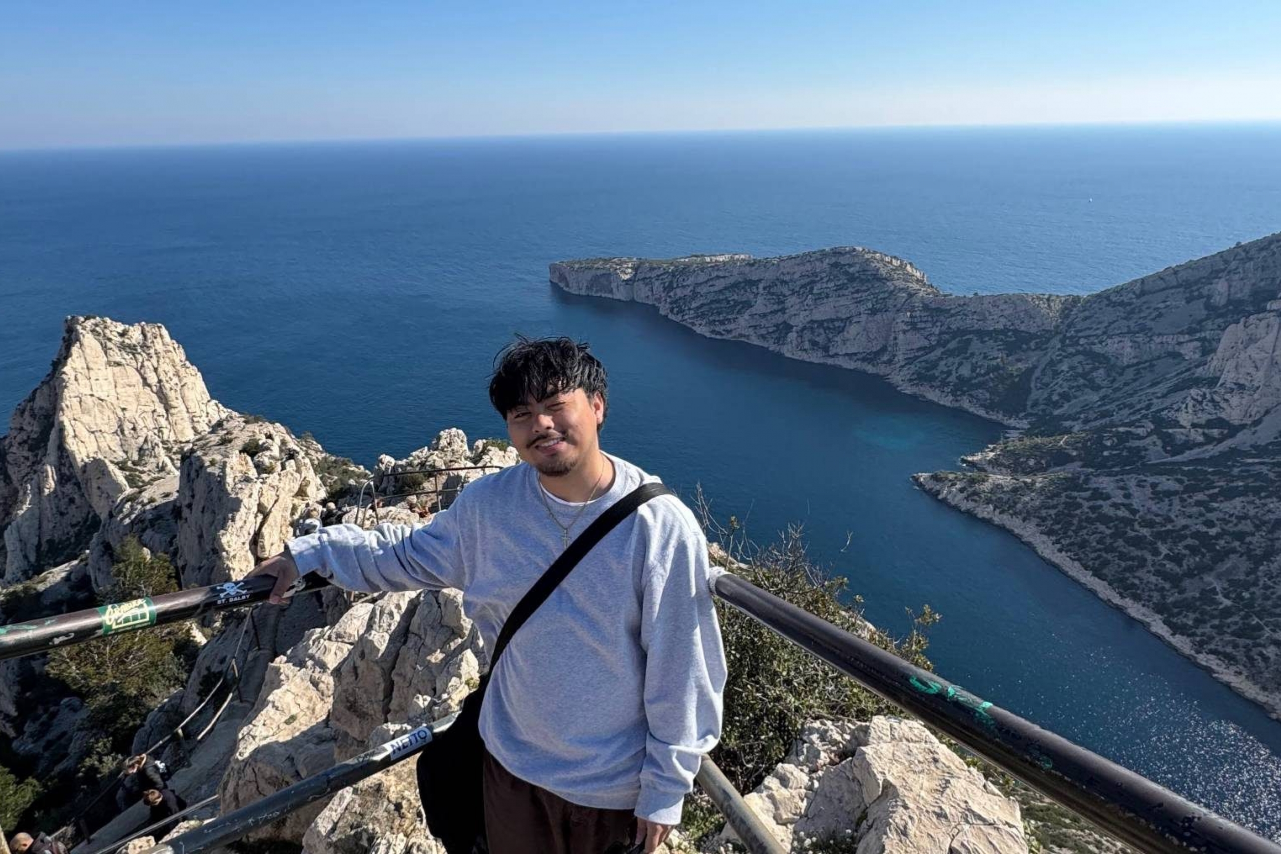 Mickael Gier smiling on a lookout with the ocean in the background