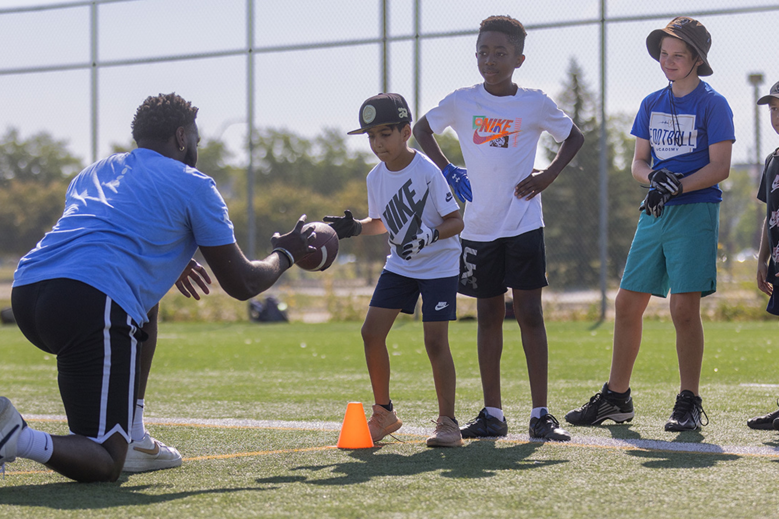 A Mini U leader coaching campers during a football game