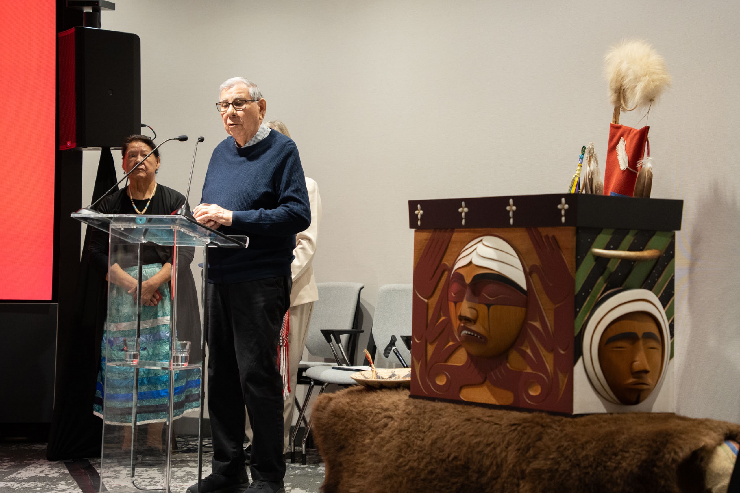 Elder Harry Bone at podium with the Bentwood Box to the right
