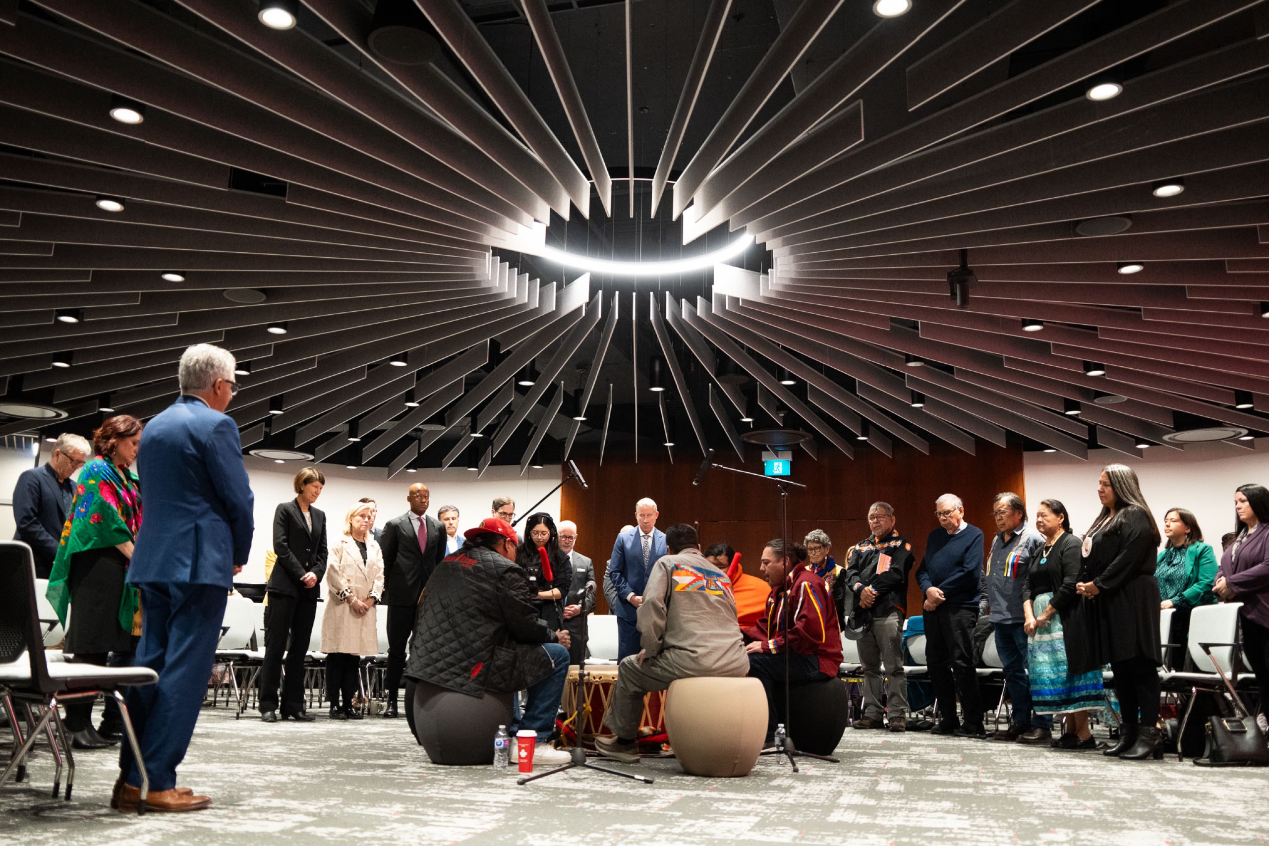 Drum circle in the middle of the room with attendees standing around them