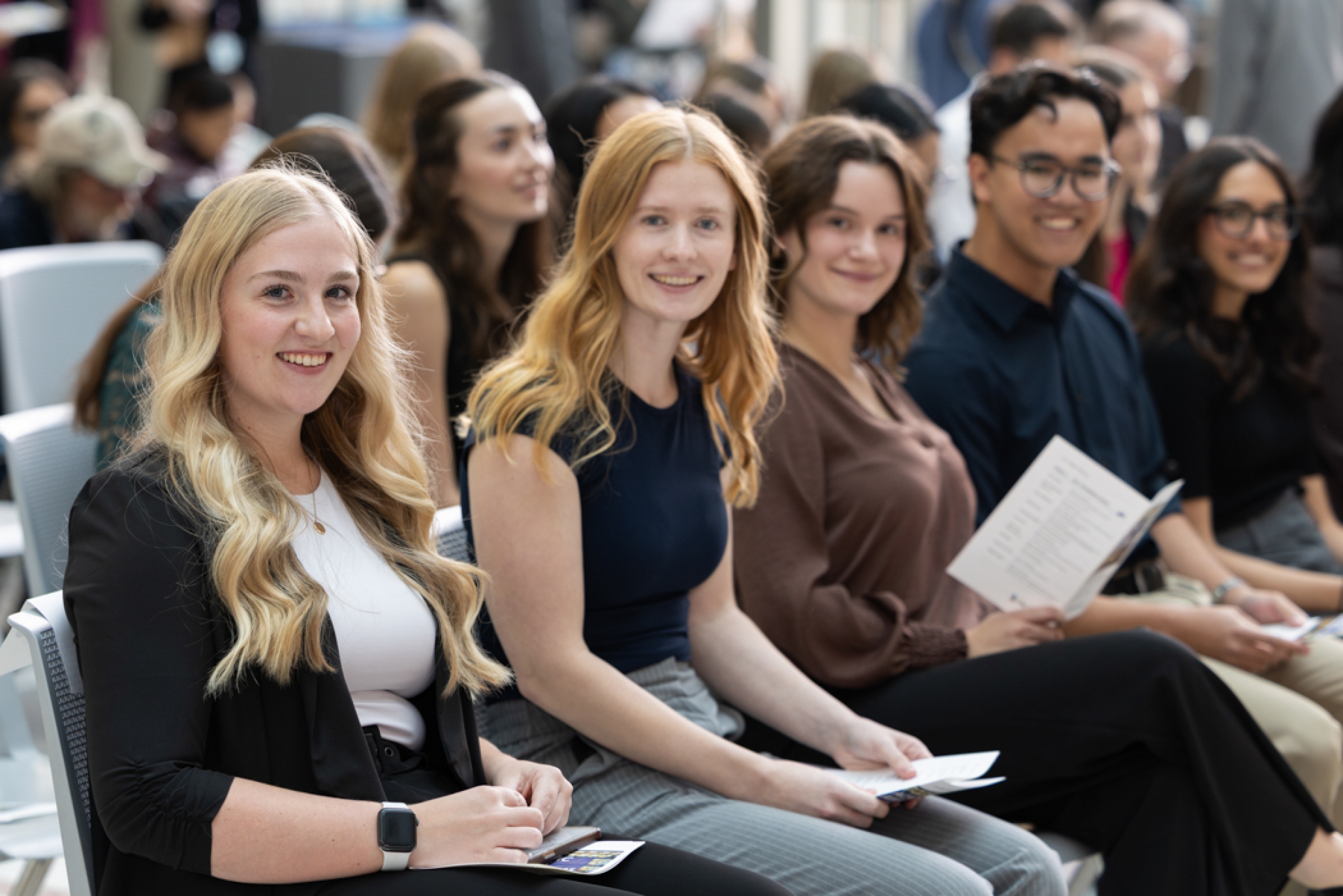 Students sit and smile at the camera.