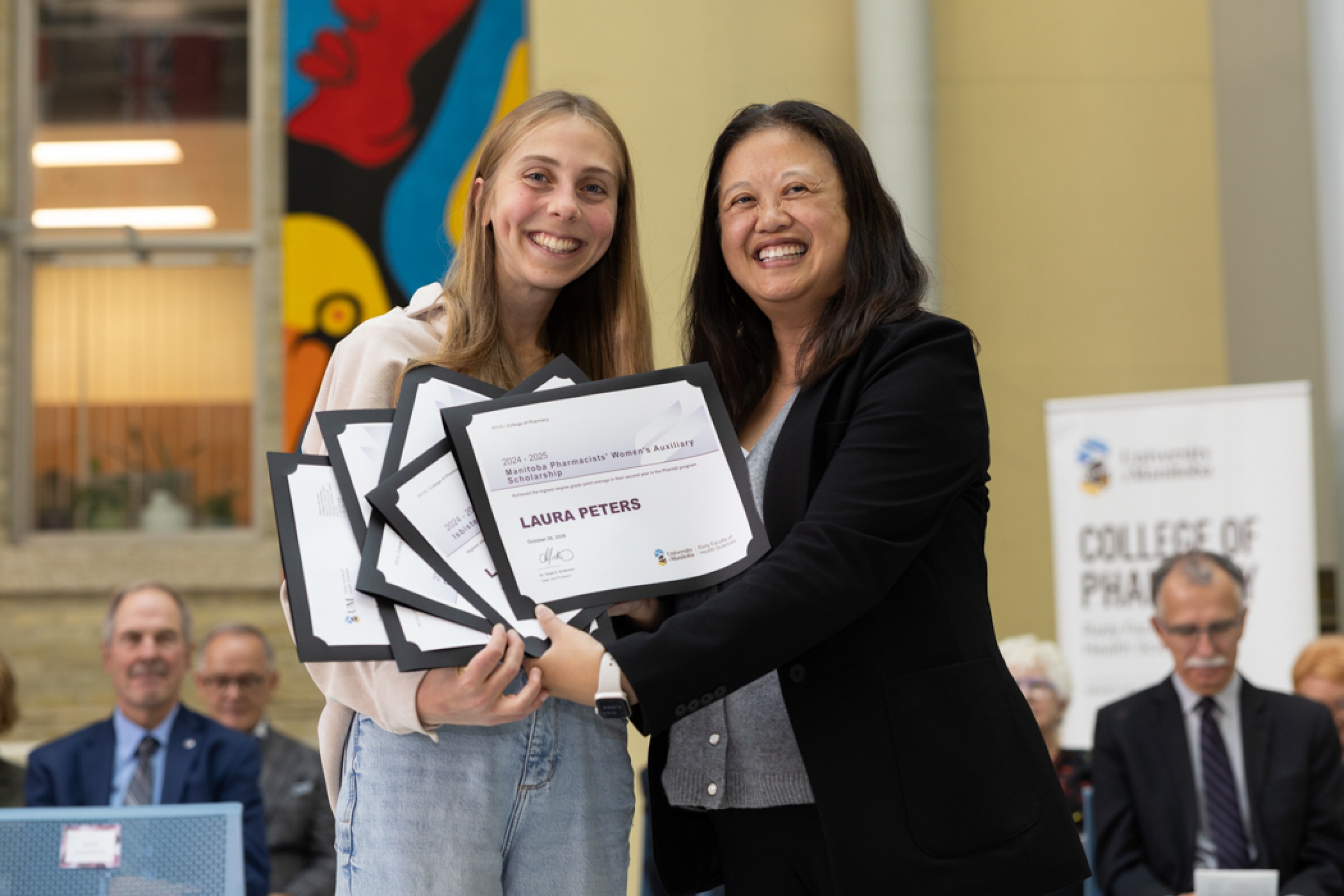 Laura Peters and Dr. Hope Anderson smile at the camera while holding Peters’ award certificates.