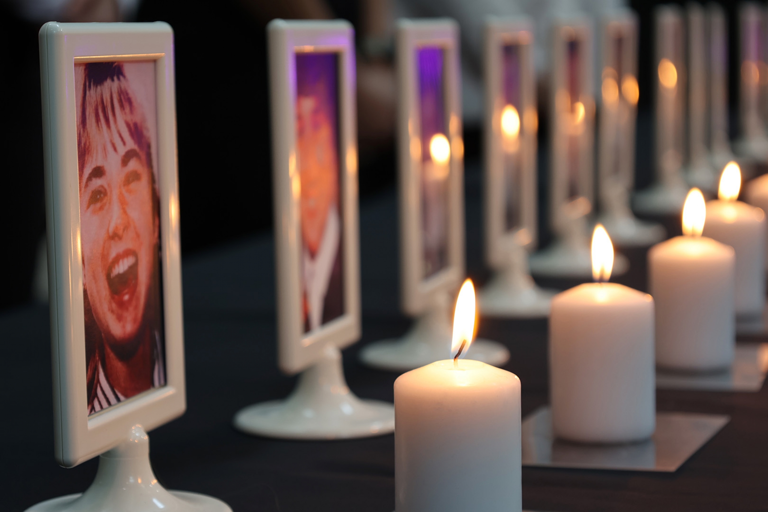 lit candles in front of photo frames of women