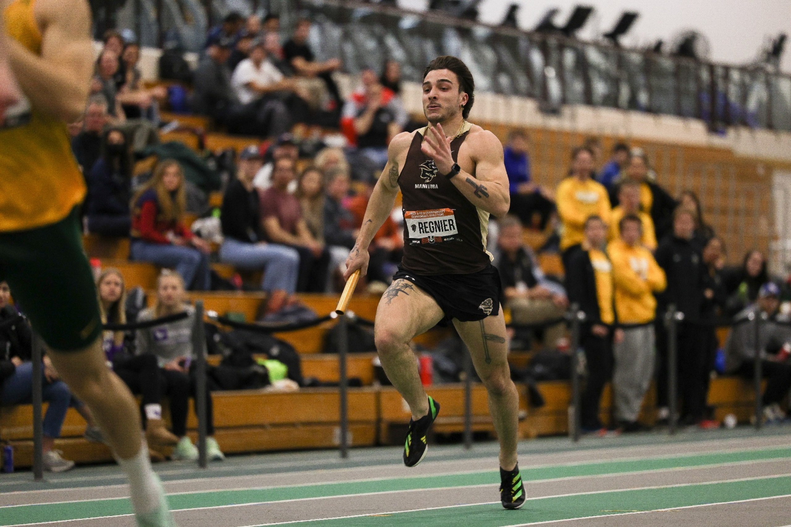 A sprinter runs down the straight away with a relay baton in hand.