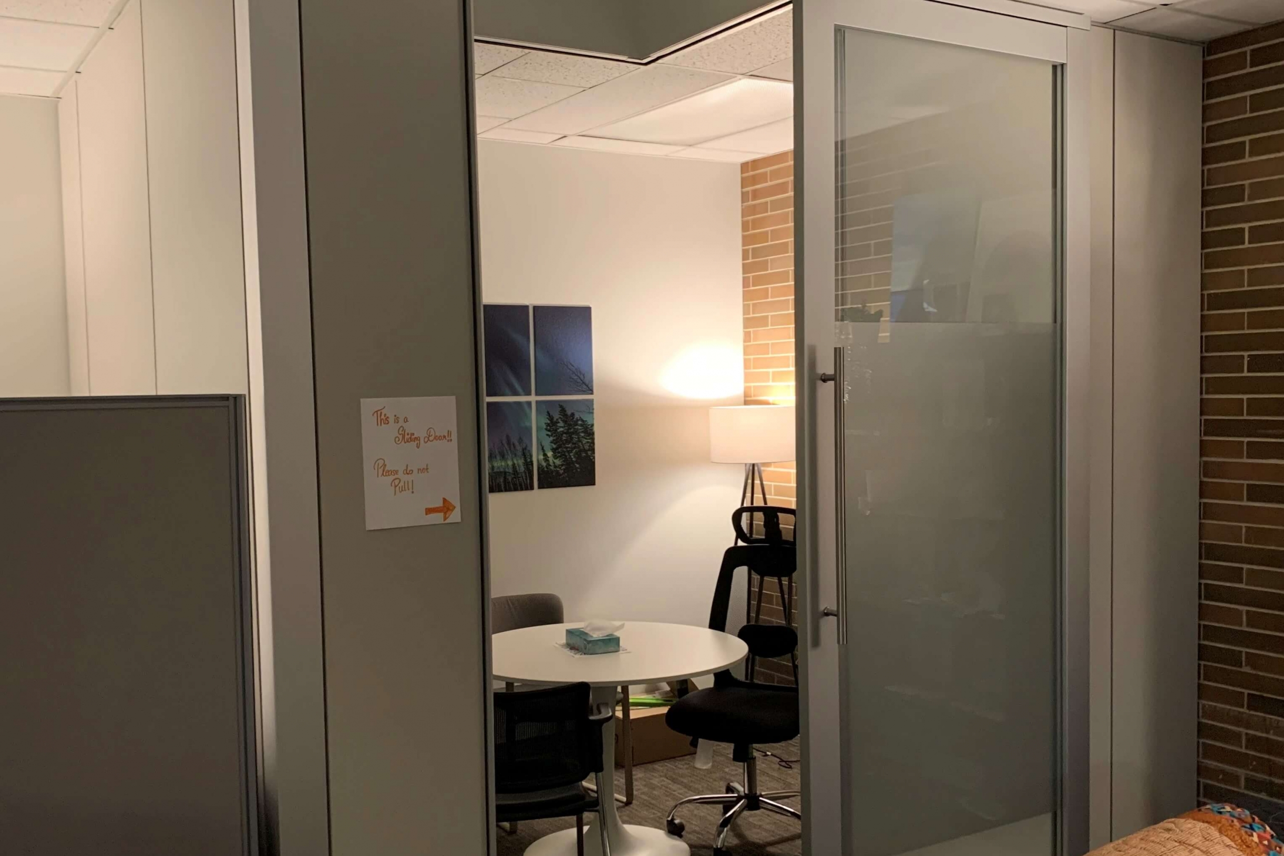 A partially open door reveals a quiet room with a chair and table.