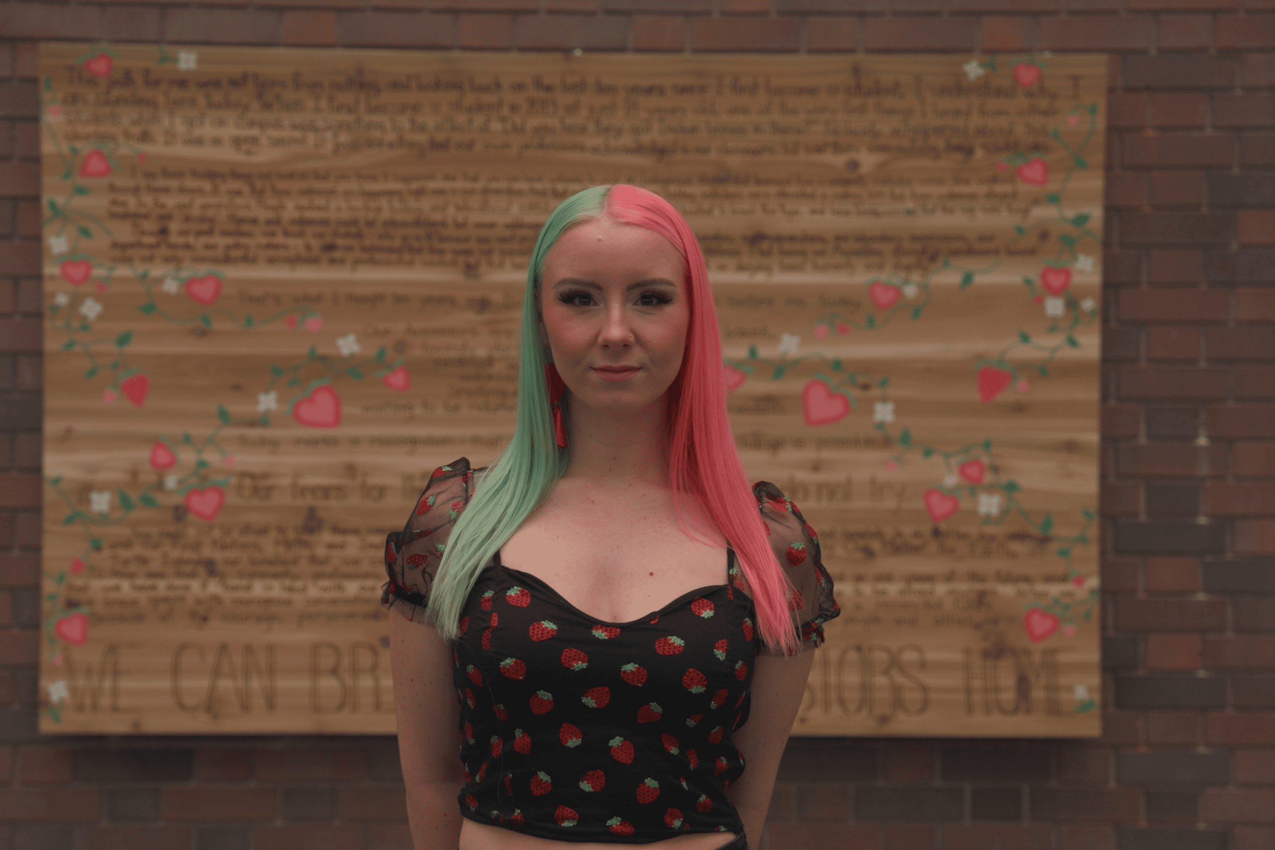 Artist stands in front of cedar board artwork.