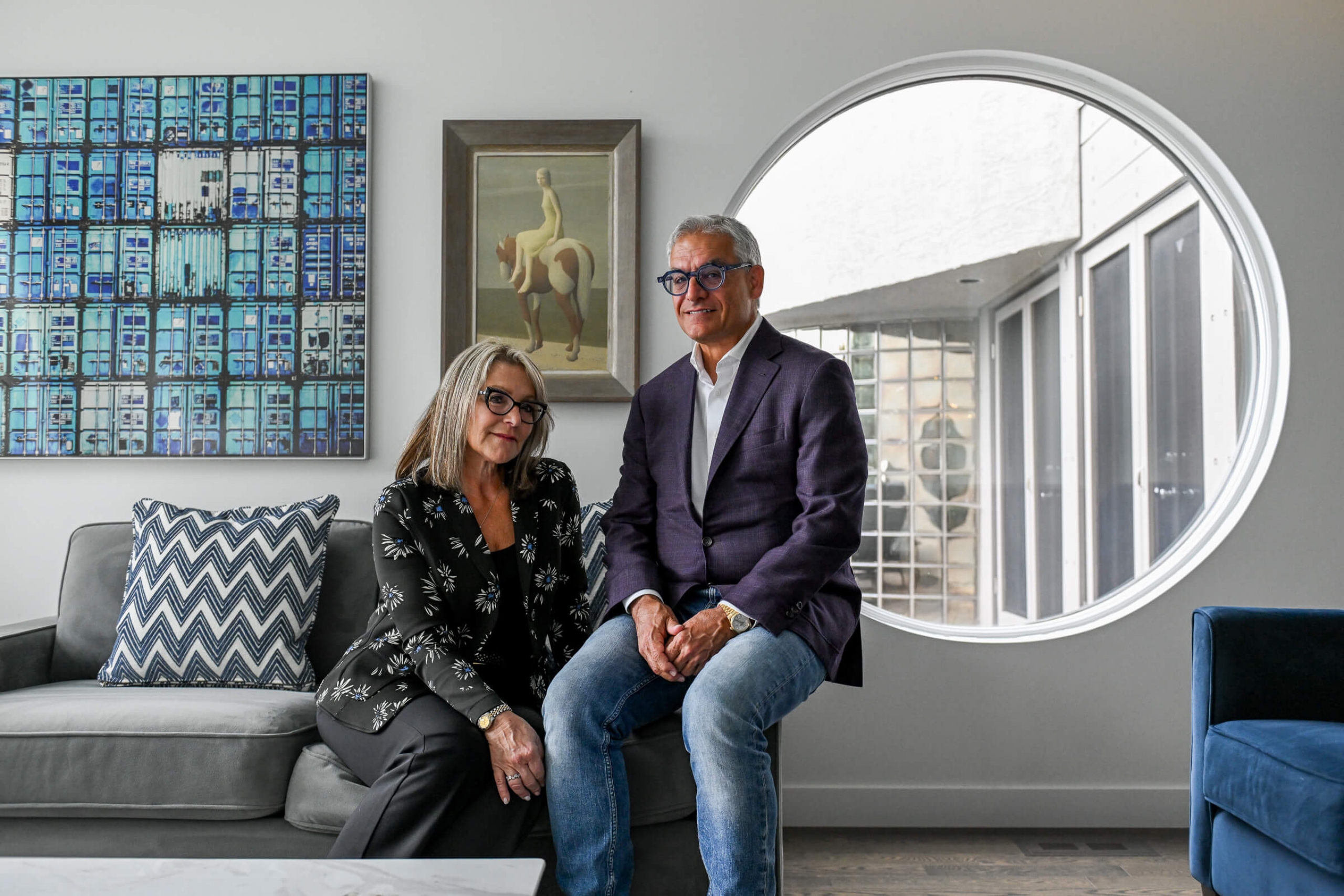 A man and woman with glassses sit next to each other on a couch