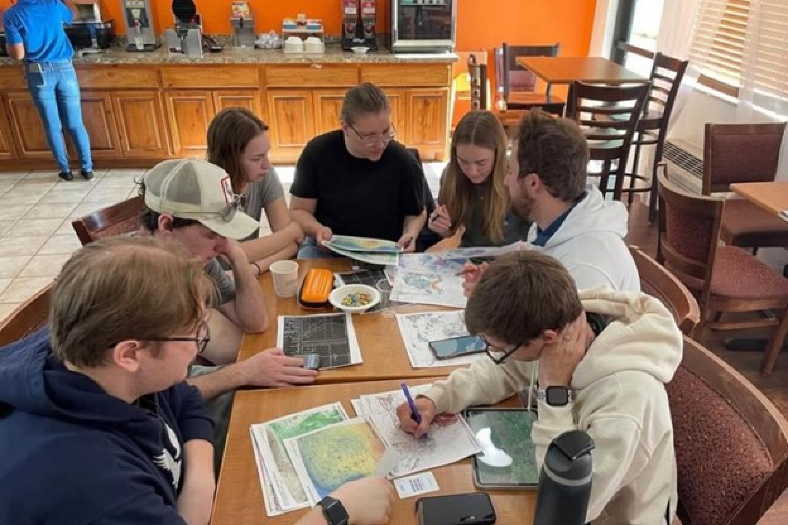A group of students are preparing for the field by looking at various maps and data.