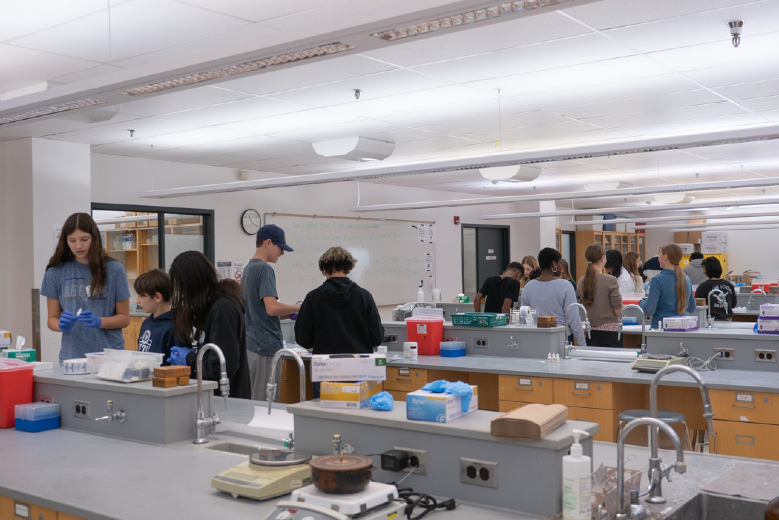 Group of students performing a hands-on activity, making lip balm and sunscreen in a lab environment.