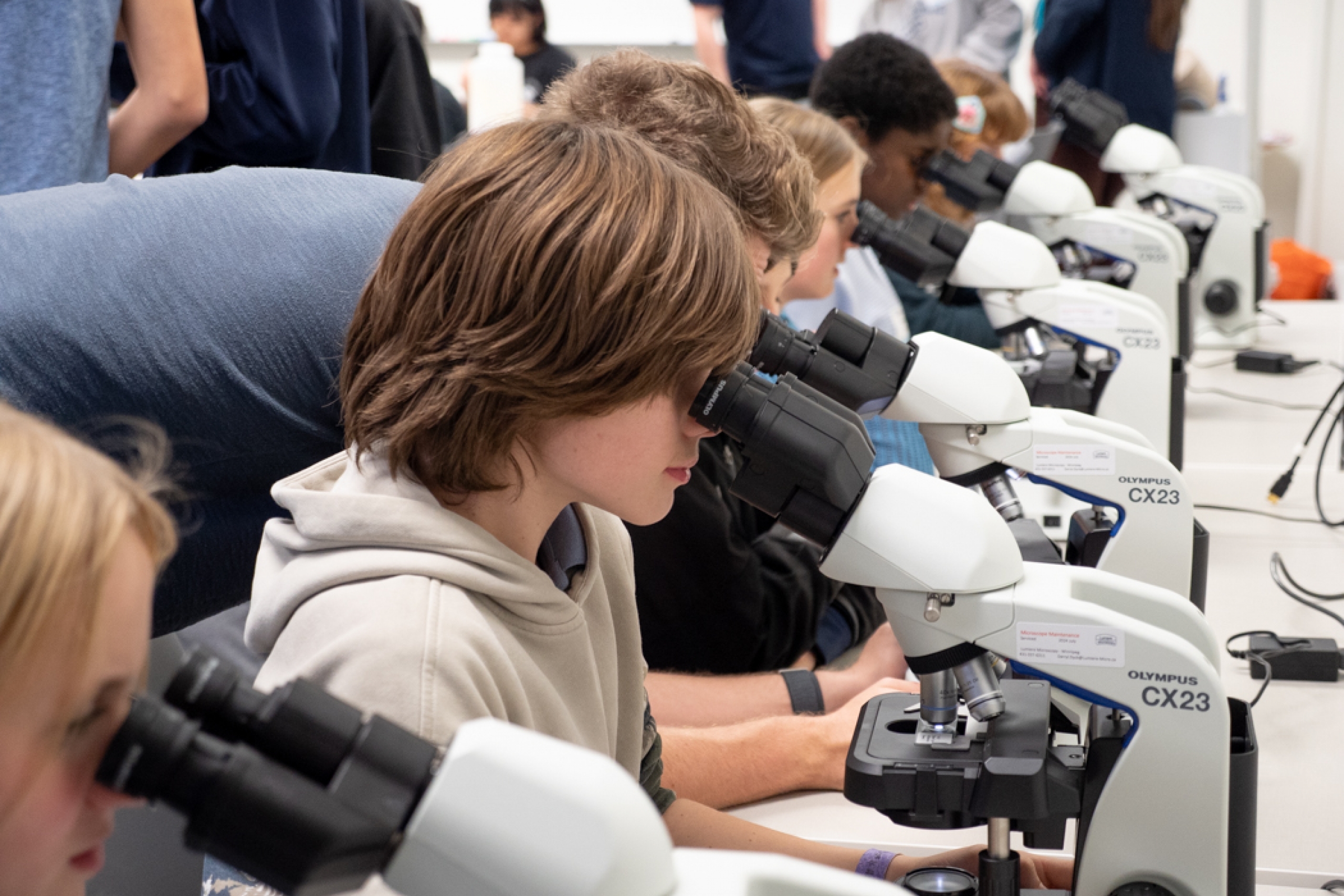 Group of students in a classroom using microscopes.