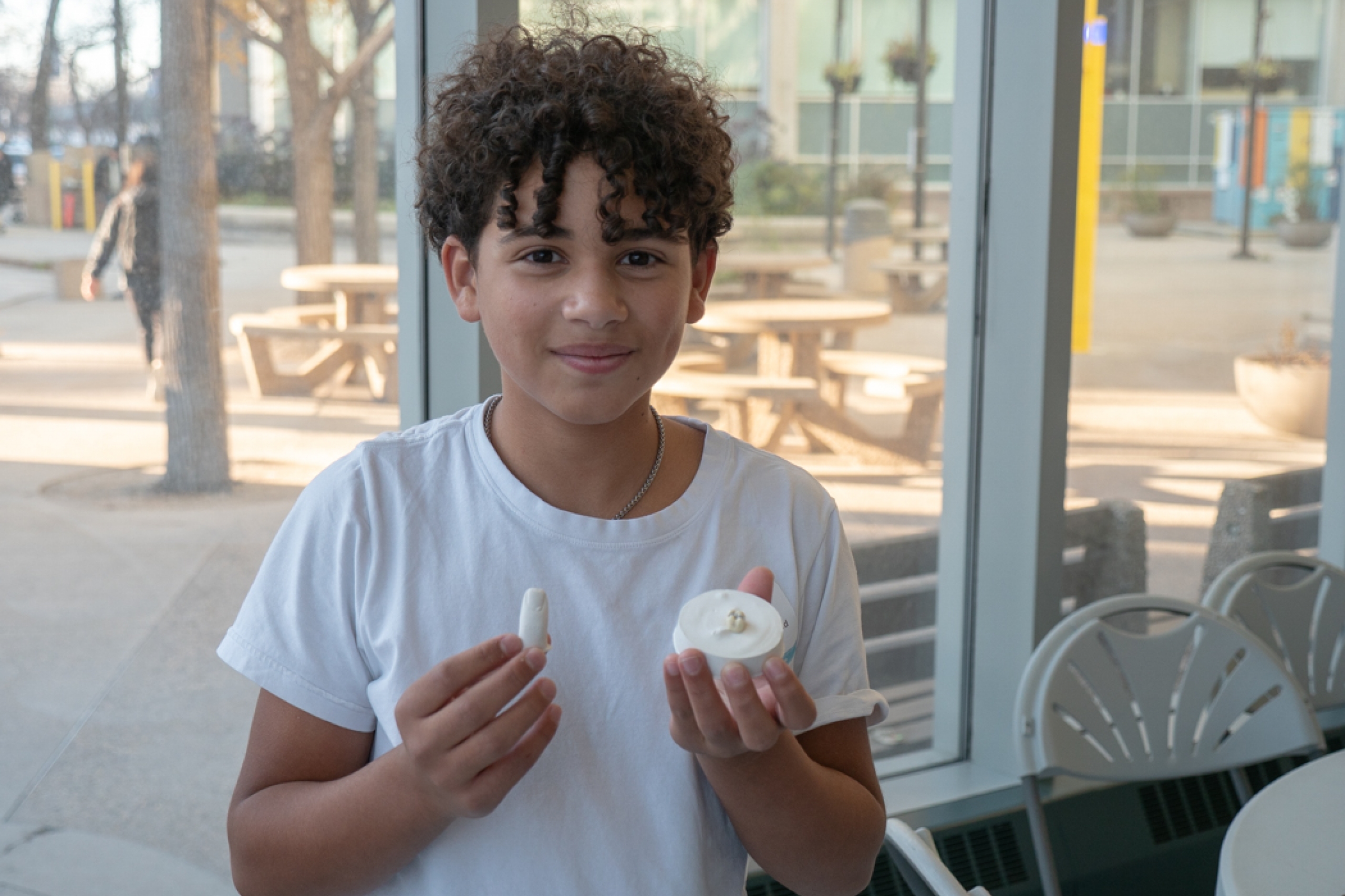 Grade 9 student smiling at the camera while holding a finger mould and a tooth model used for a filling exercise.