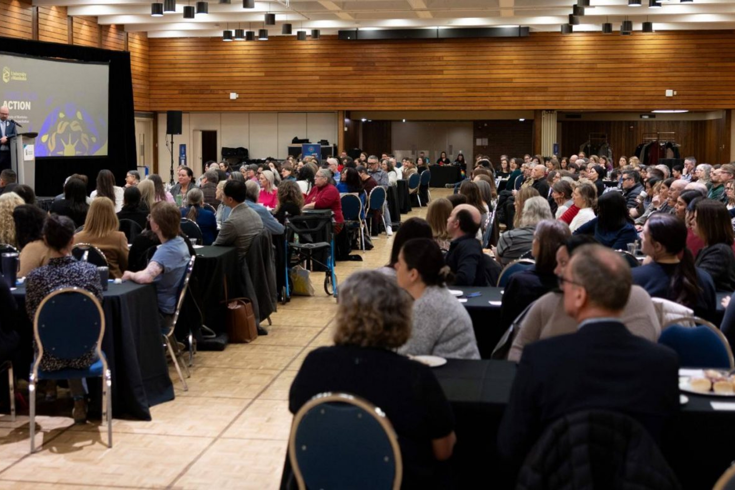 A full ballroom watches the speakers discuss on stage.