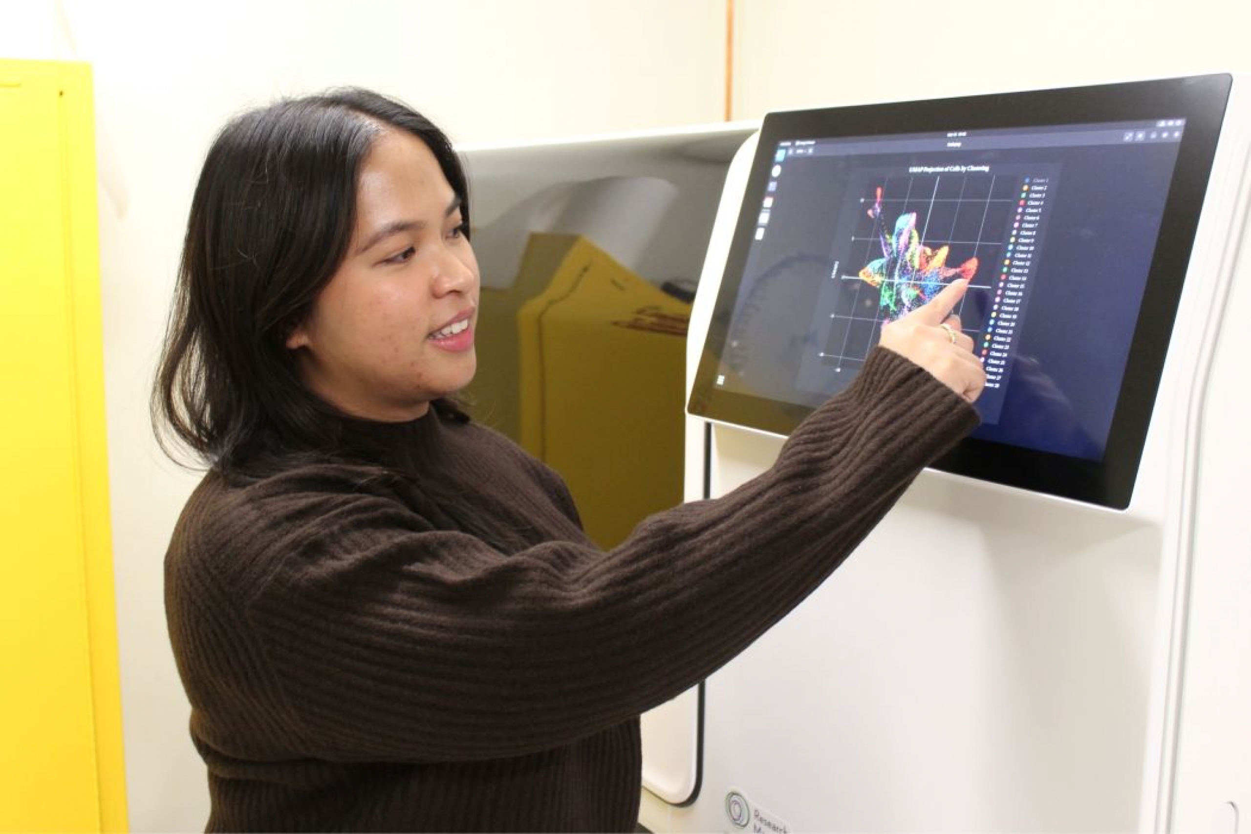 Deanne Nixie Miao presses a touch screen on a machine. There is a graphic on the screen.