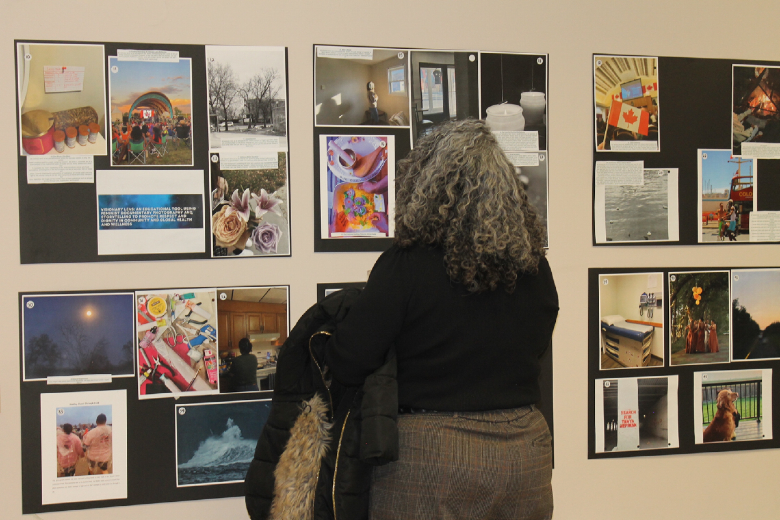 A person stands in front of collaged photos at a photography exhibit.