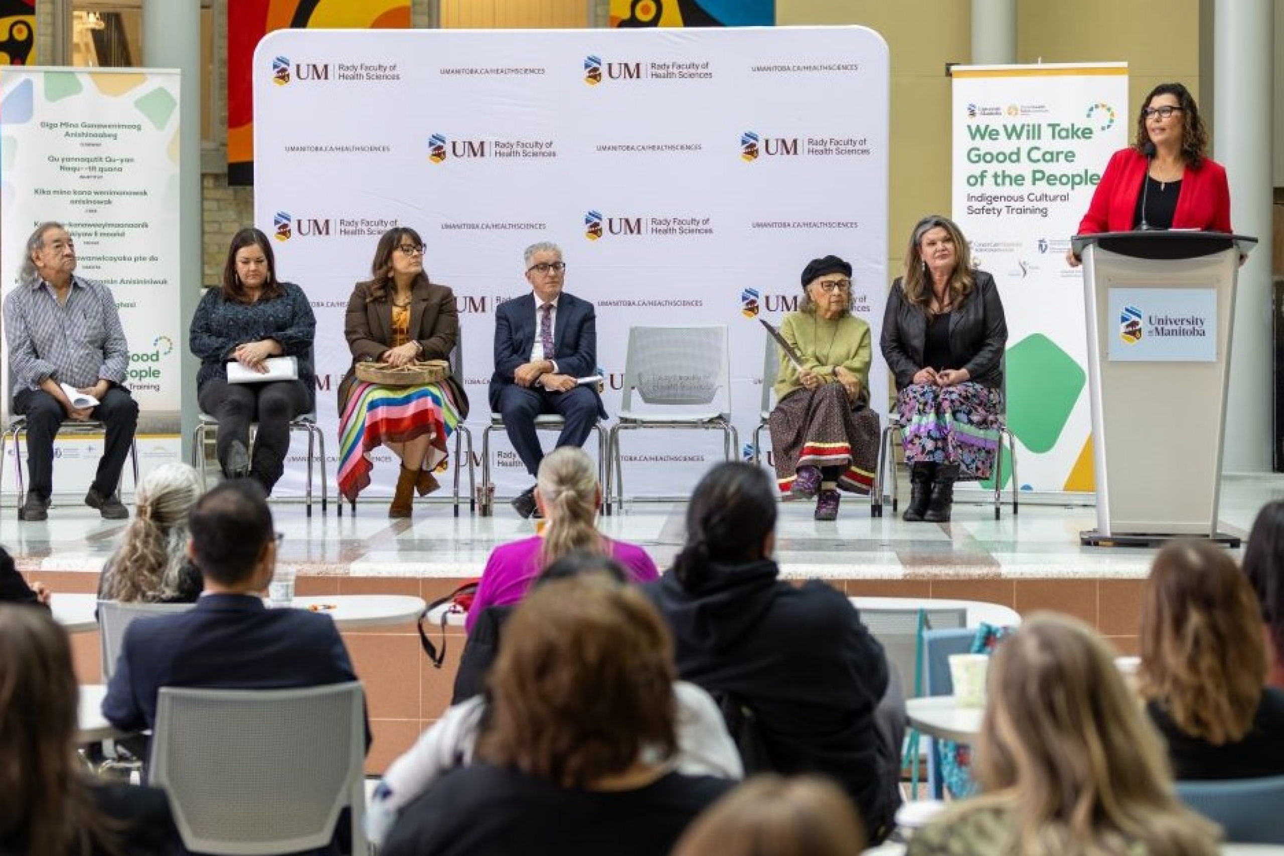 Dr. Marcia Anderson speaks at a podium as other speakers look on.
