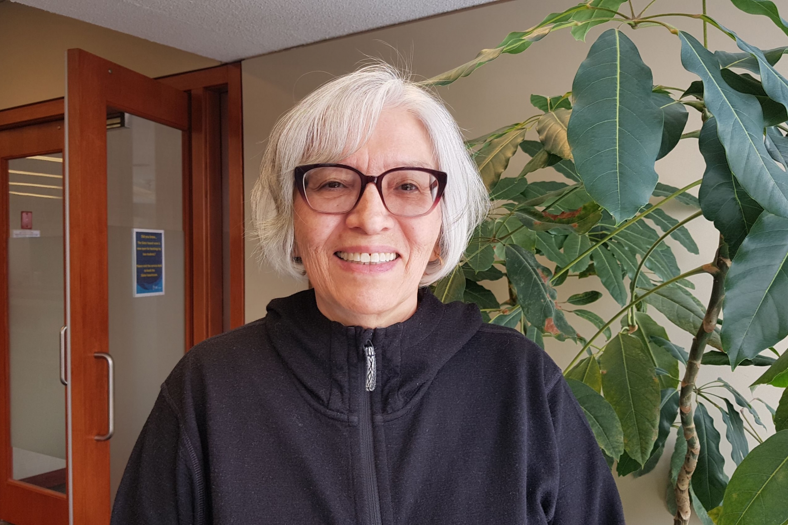 Person with short grey hair smiles at camera
