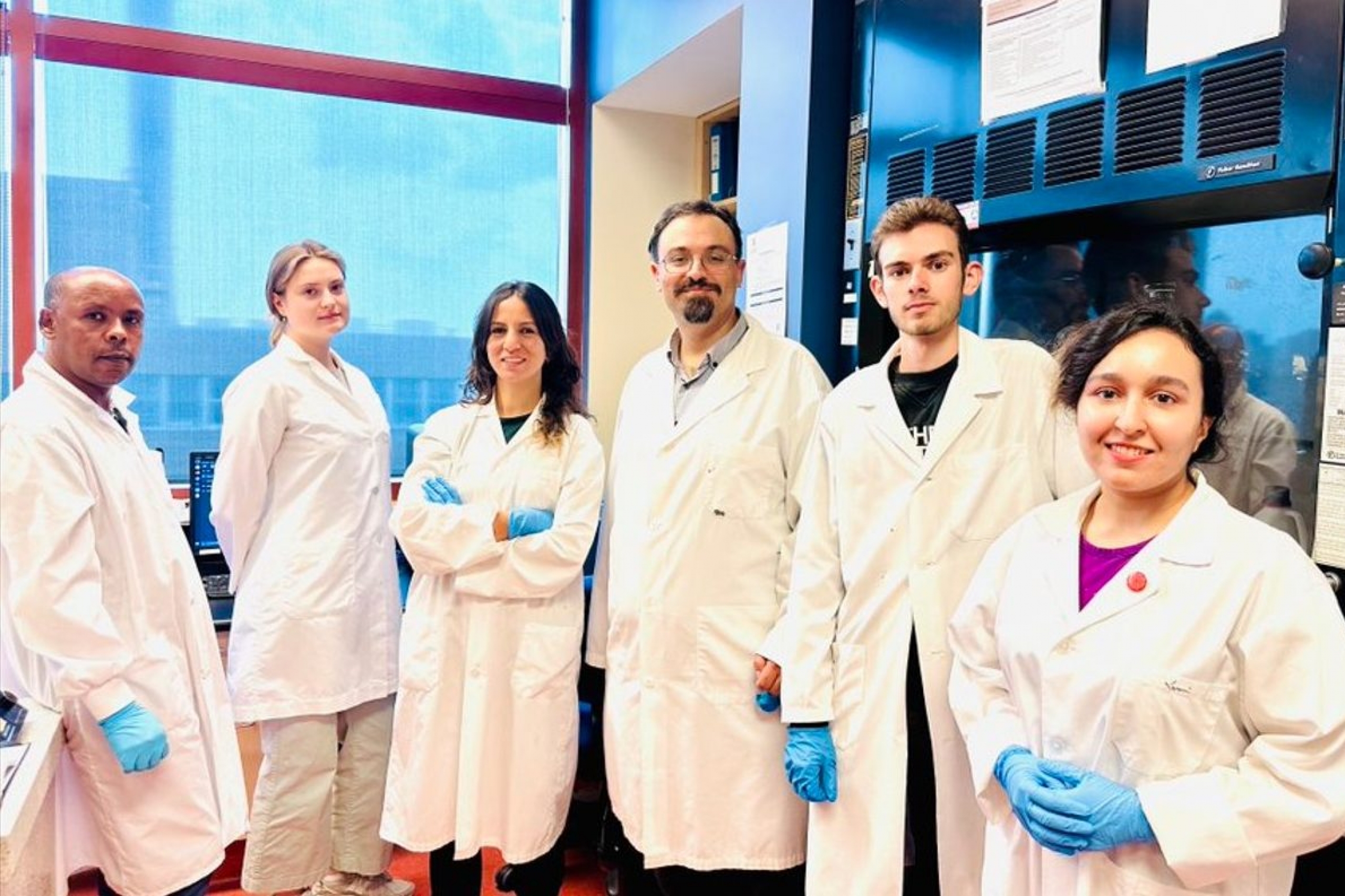 People wearing labs coats and gloves smiling in their lab.