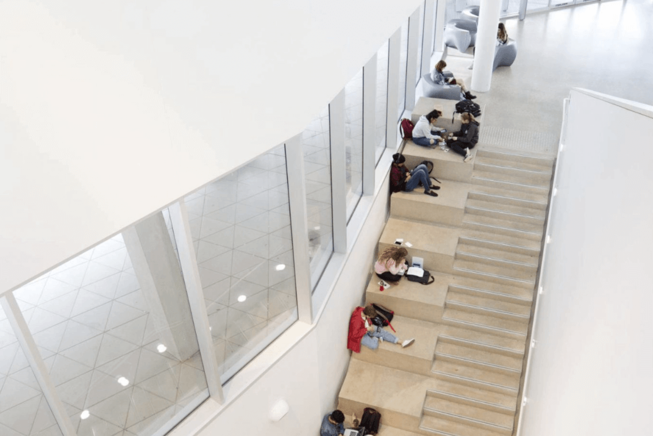 Aerial view of students sitting on the steps inside the Artlab building.