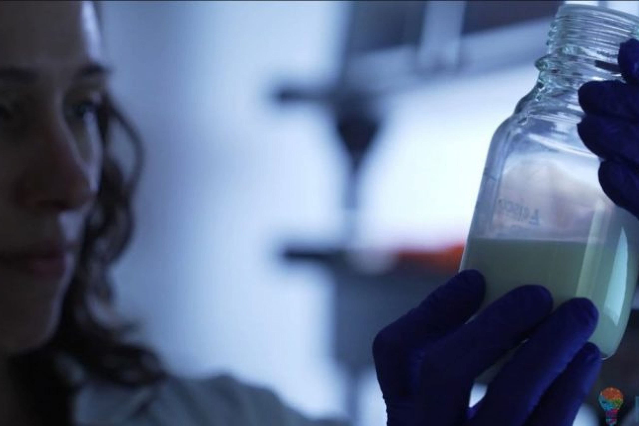 researcher looking at breast milk in a bottle