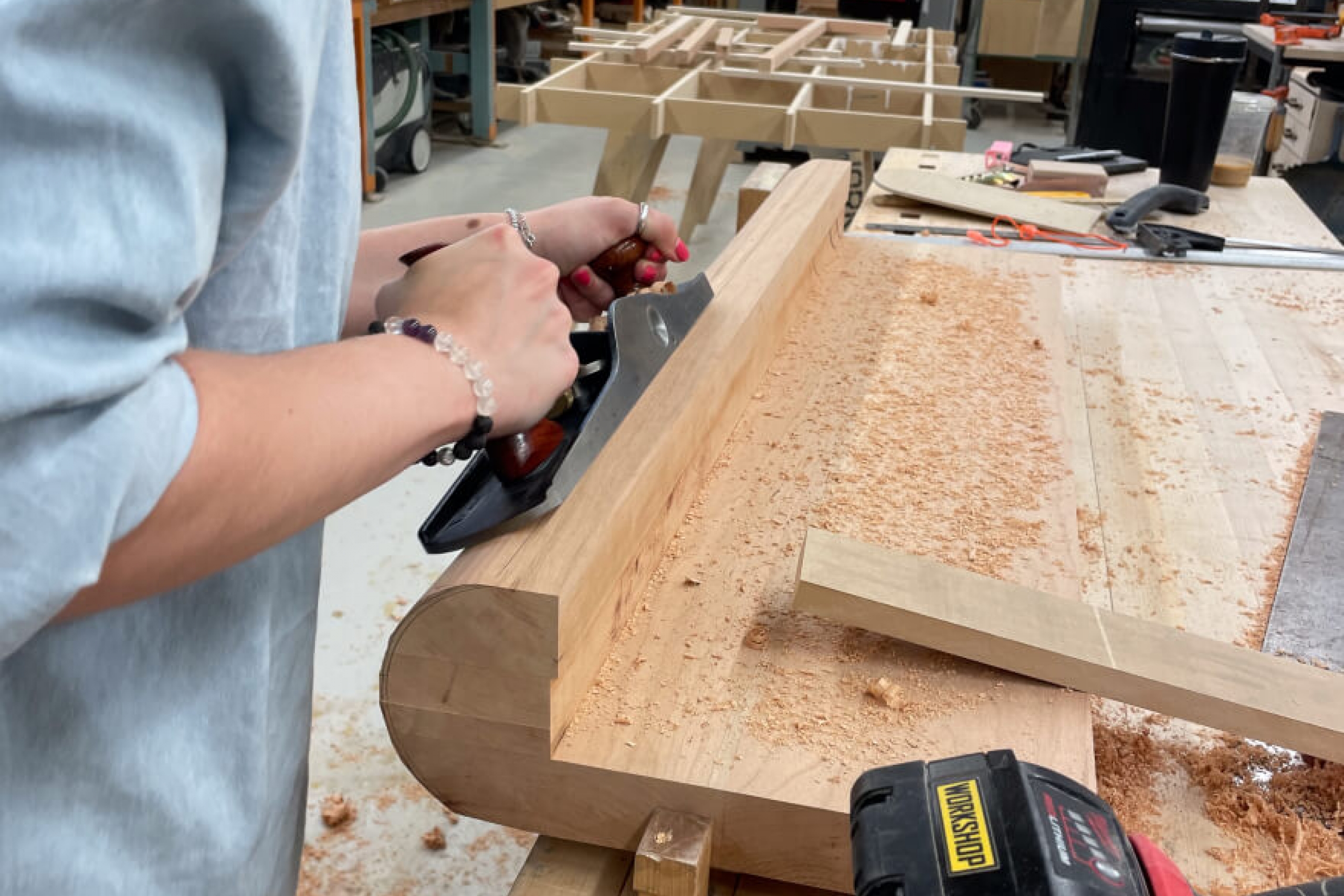 A student sanding down wood that will be part of a chair.