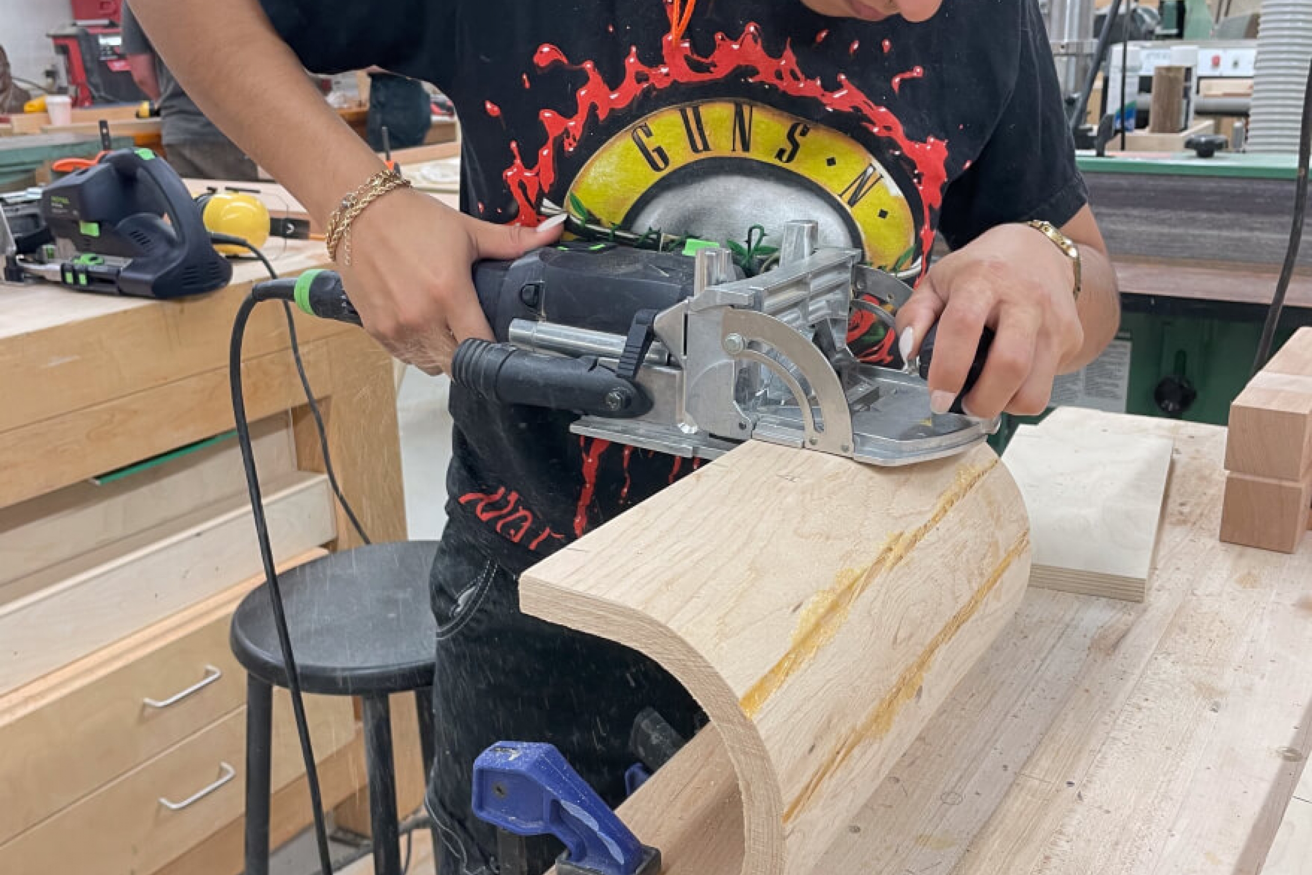 A student uses a sander on a piece of wood.