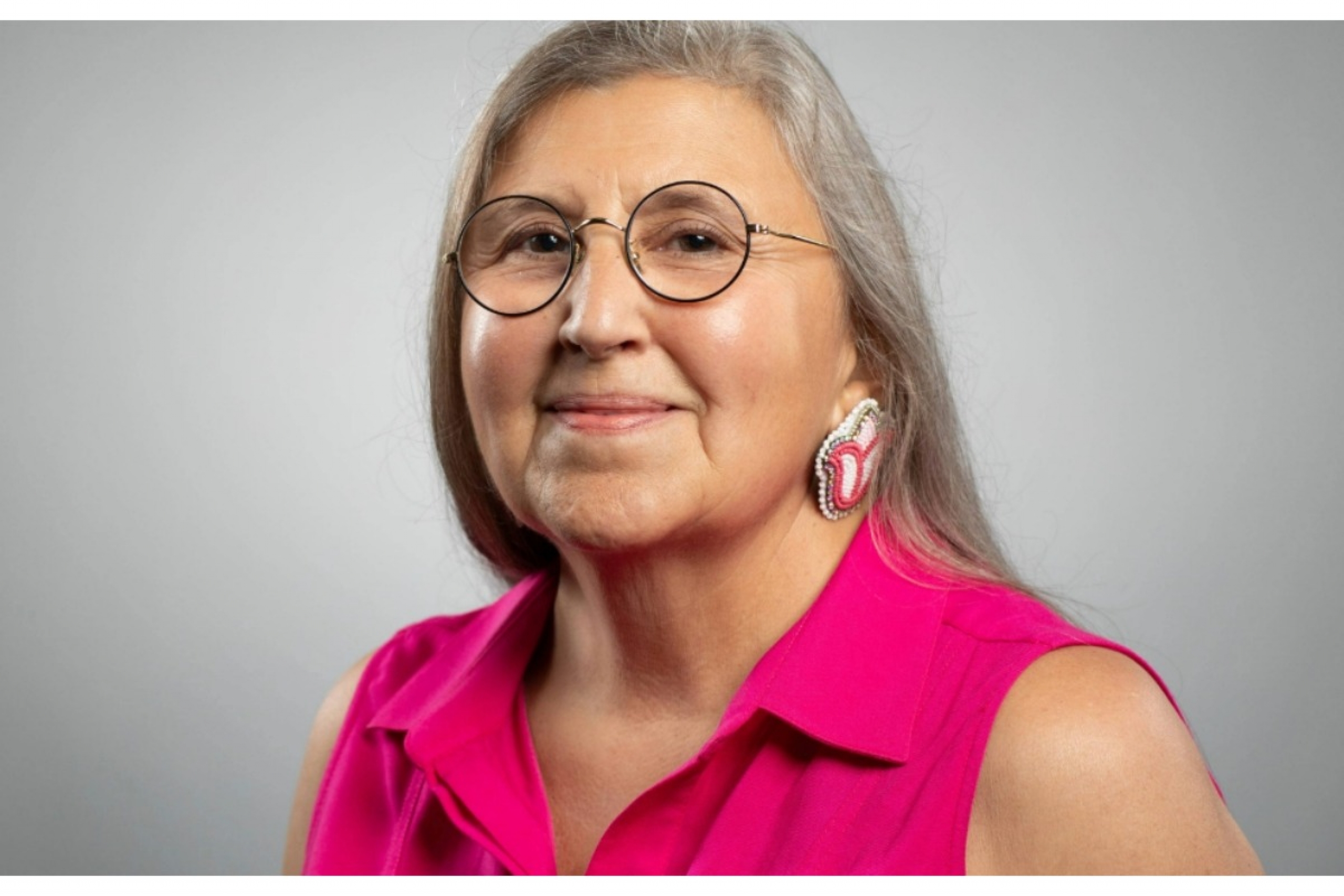 portrait of Pahan PteSanWin, wearing pink top against grey backdrop.